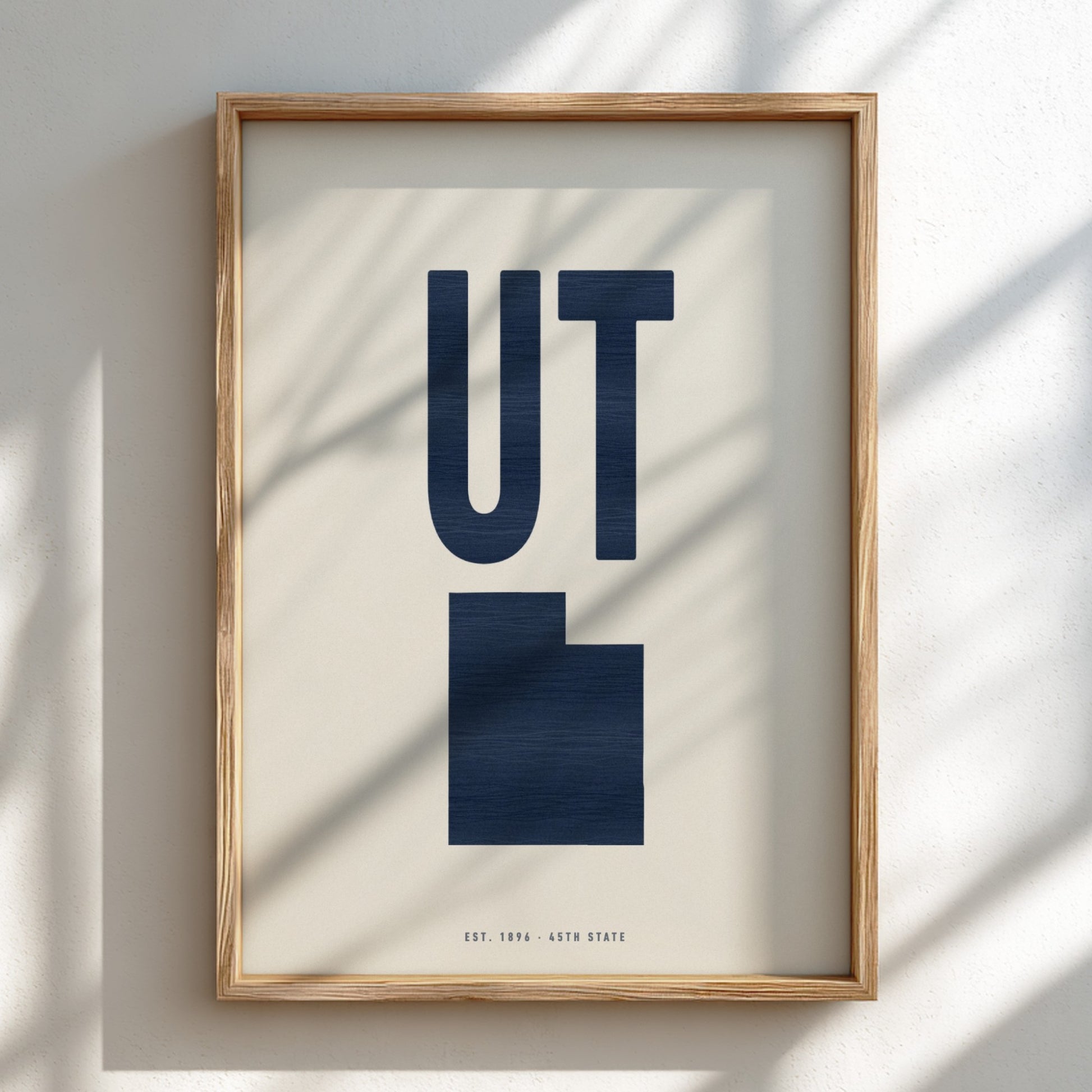 Framed artwork with 'UT' in a navy blue silhouette of Utah on a beige background