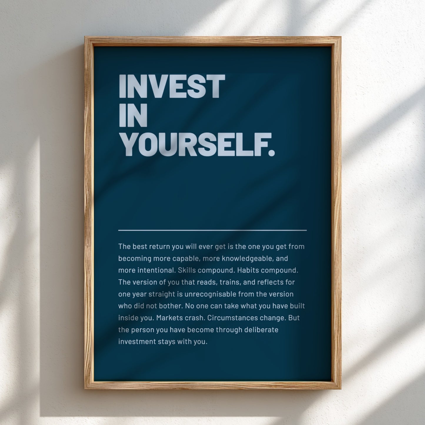 Framed poster with motivational text 'Invest in Yourself' on a blue background