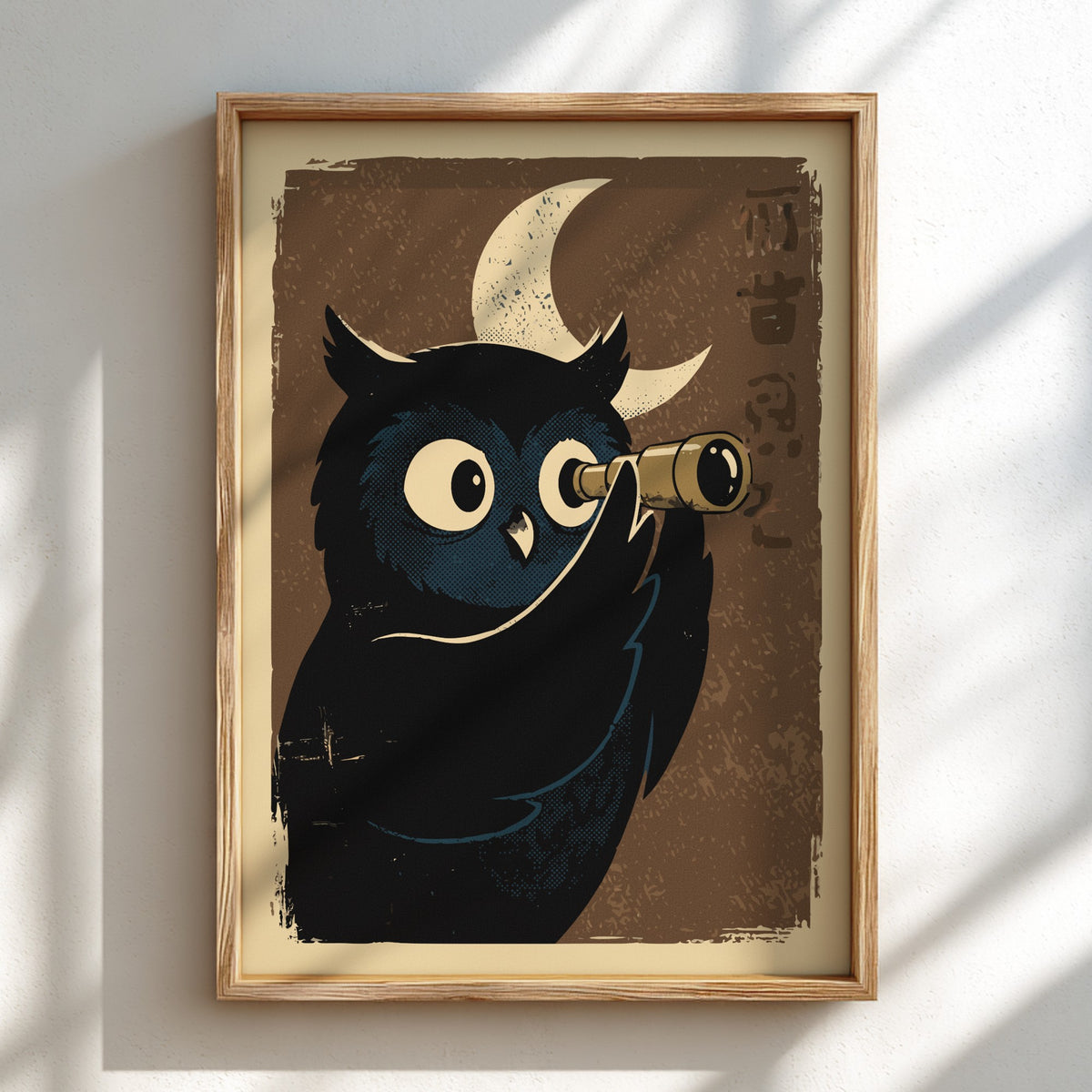 A framed art print featuring a stylized black owl with large white eyes peering through brass binoculars against a textured brown background with a cream crescent moon. The print is housed in a light natural wood frame and mounted on a white wall with soft diagonal shadows.