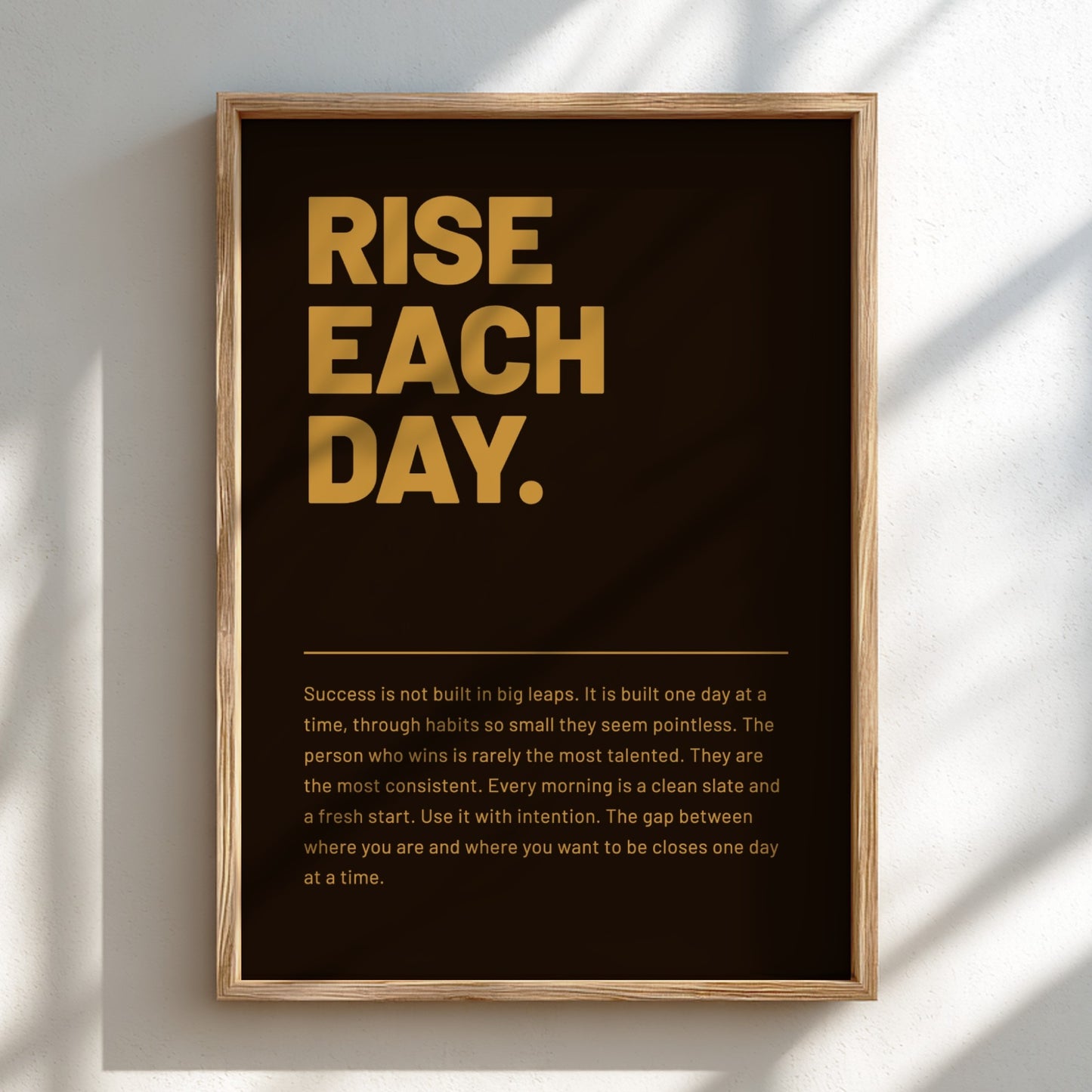 Framed poster with motivational quote 'RISE EACH DAY.' on a dark background
