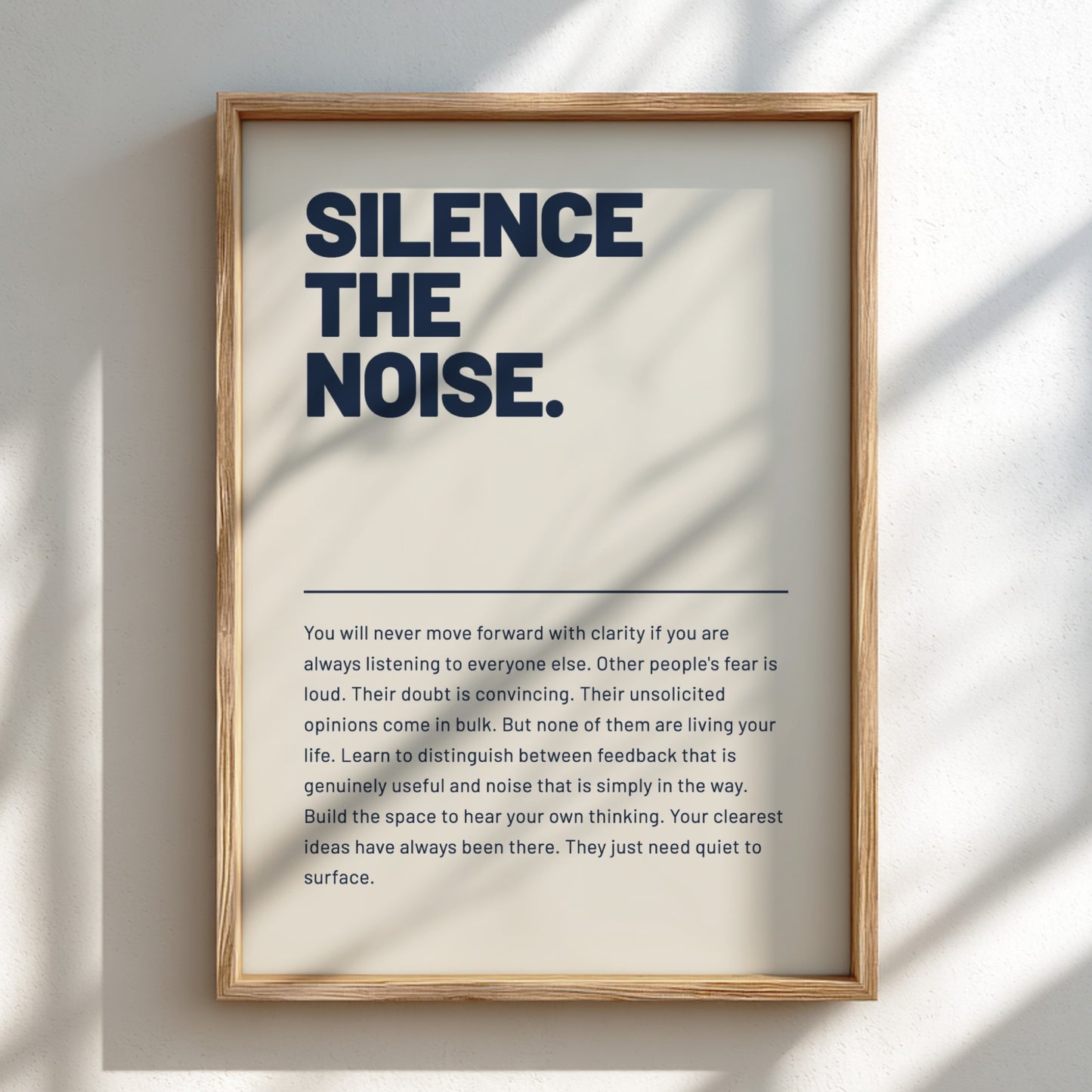 Framed poster with motivational quote 'Silence the Noise' on a light background