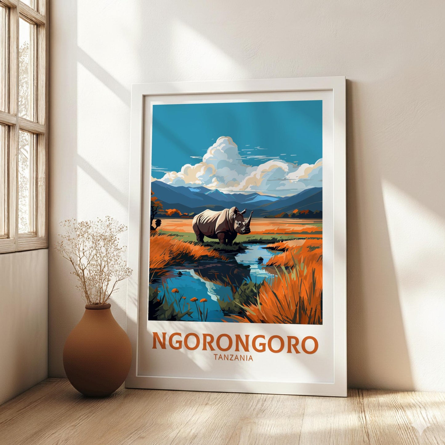 Framed artwork of a rhino in a natural landscape with 'Ngorongoro Tanzania' text, placed on a wooden floor.