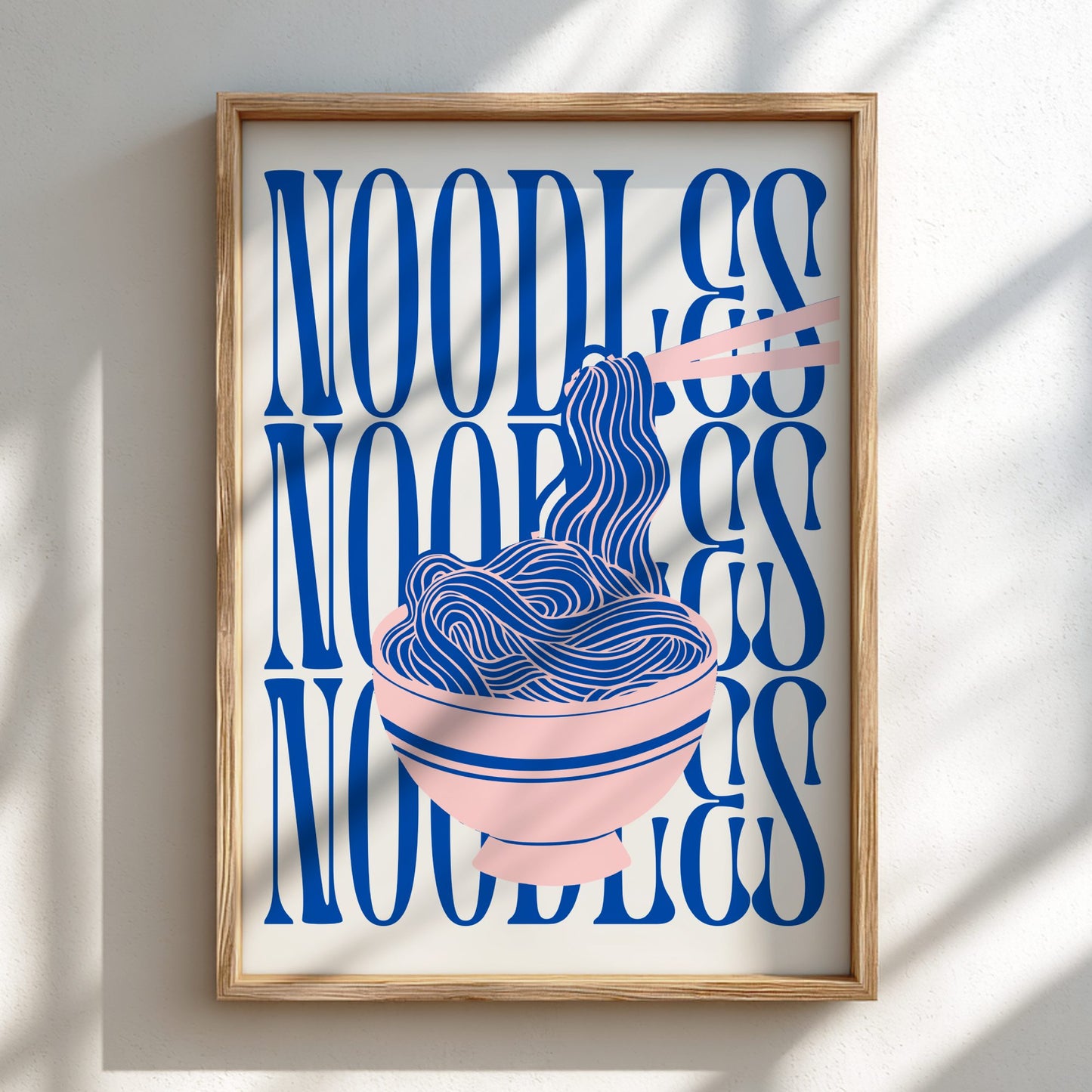 Framed artwork with blue text and illustration of noodles on a white wall.