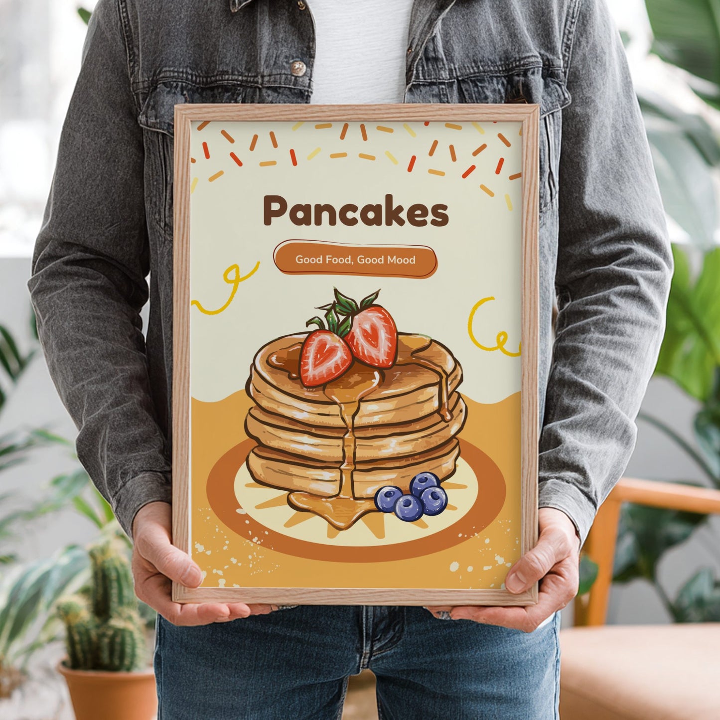 Person holding a framed illustration of pancakes with strawberries and blueberries.