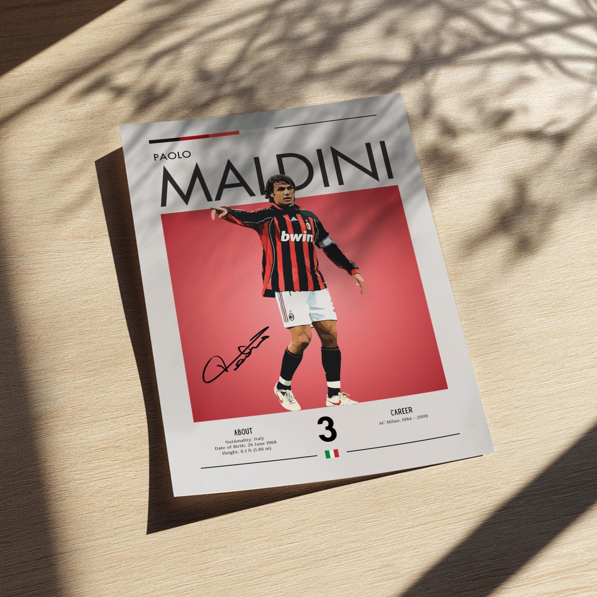 Framed poster of a soccer player in a red and black striped jersey on a light wooden surface.