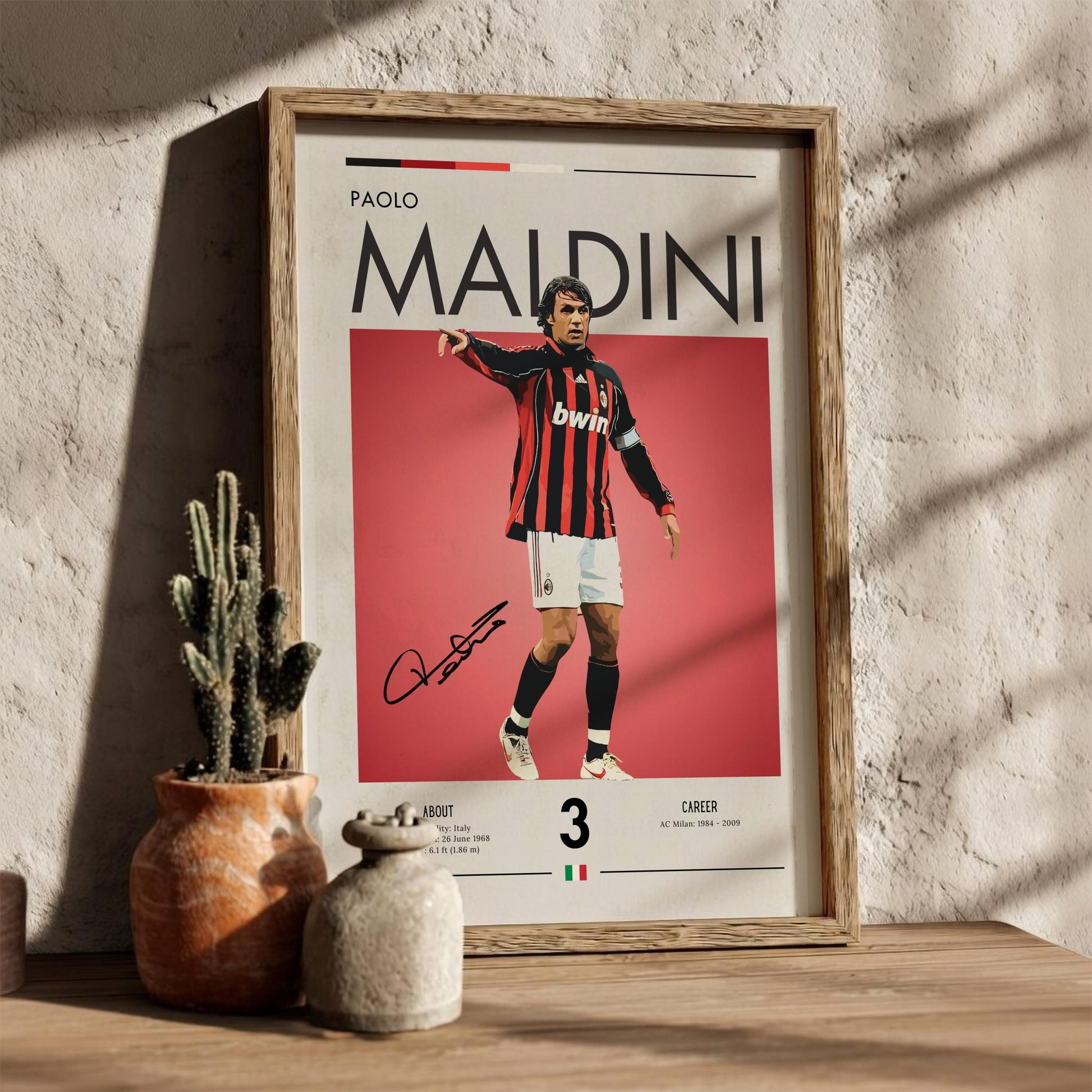 Framed poster of Paolo Maldini with a red background, placed on a wooden surface with decorative items.