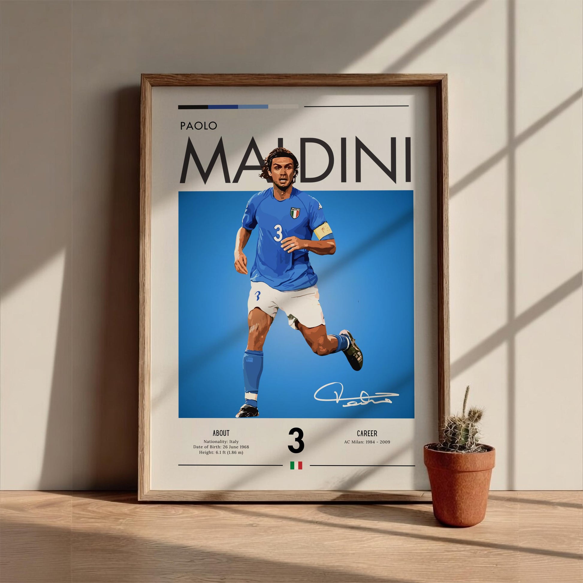 Framed poster of a soccer player in a blue jersey with Italian flag design, placed on a wooden surface with a plant.