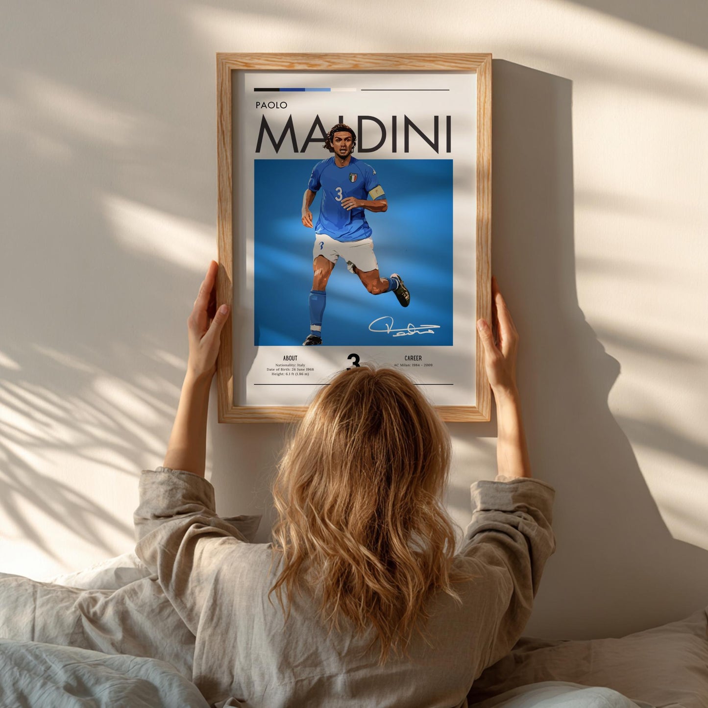 Person hanging a framed picture of a soccer player on a wall