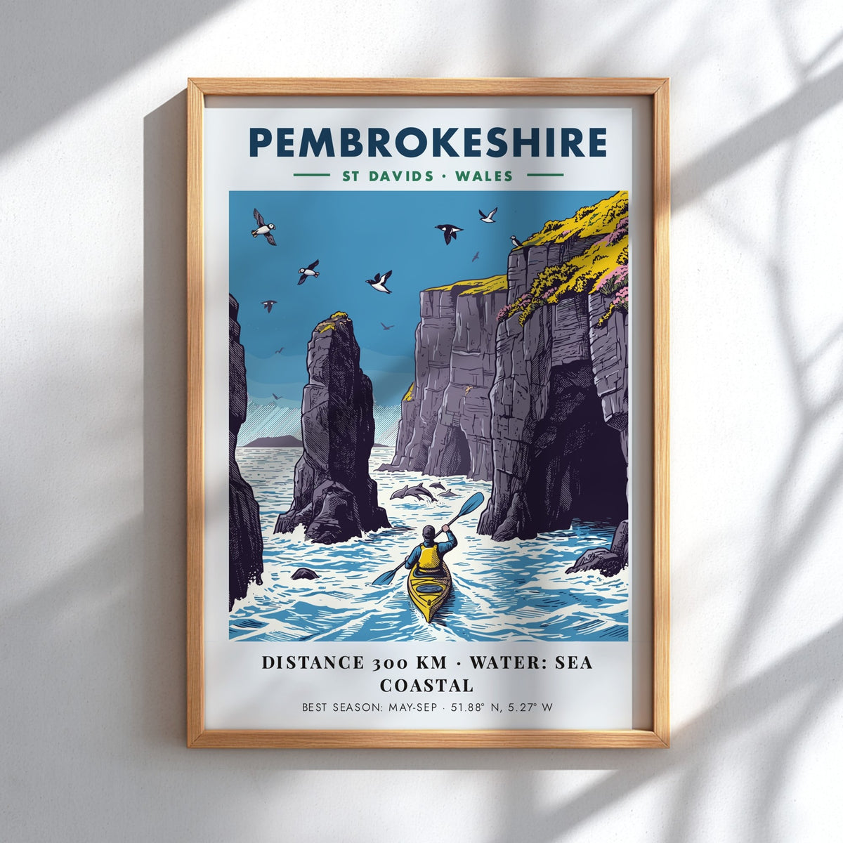 Poster featuring a kayaker paddling near tall Pembrokeshire sea cliffs with blue water.