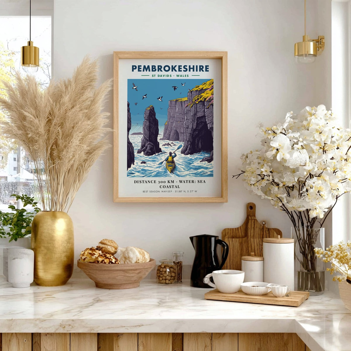 Poster featuring a kayaker paddling near tall Pembrokeshire sea cliffs with blue water.
