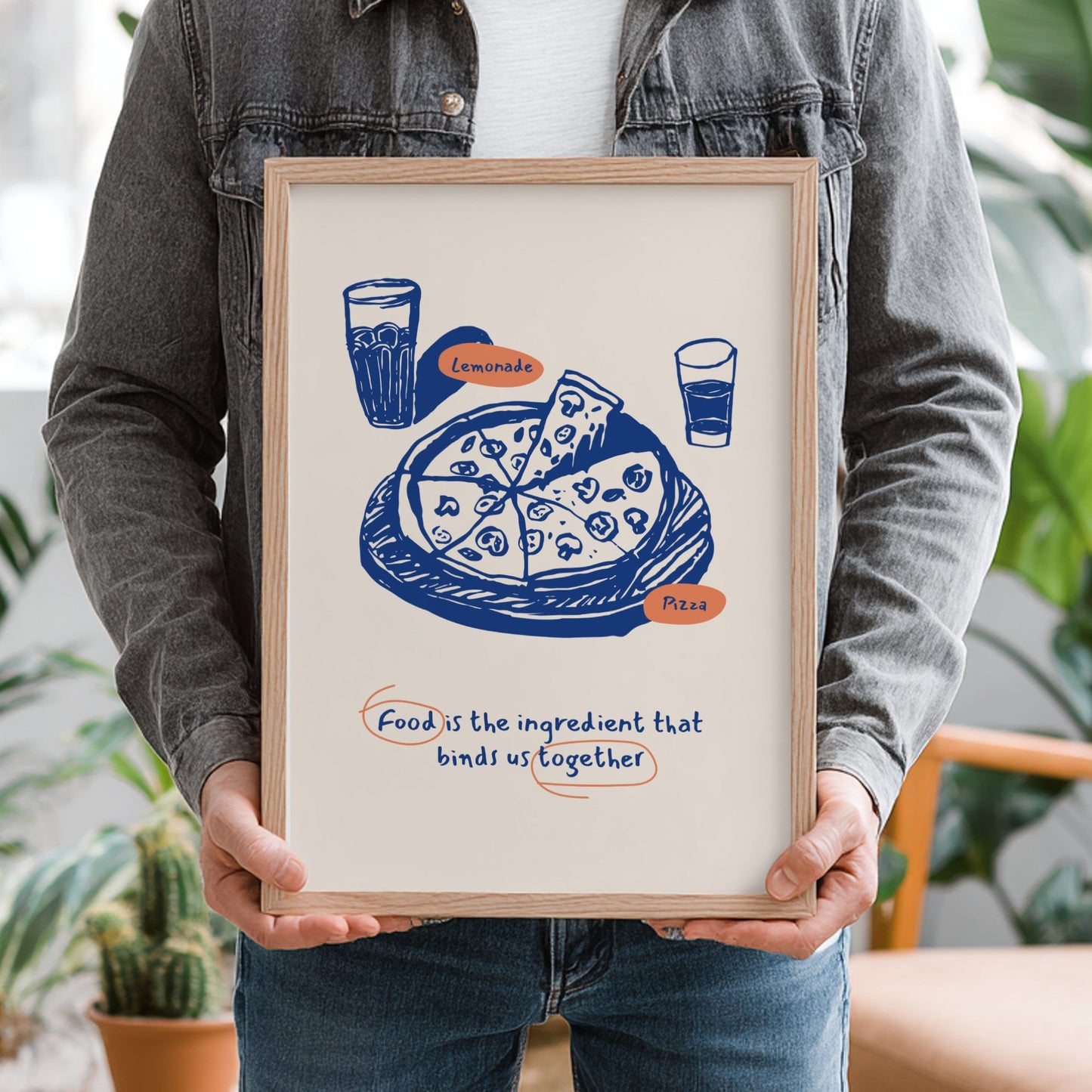 Person holding a framed illustration of pizza and lemonade with text.