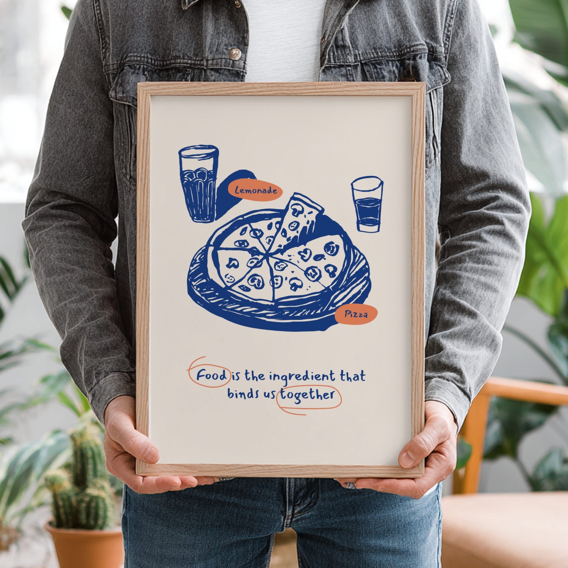 Person holding a framed illustration of pizza and lemonade with text.