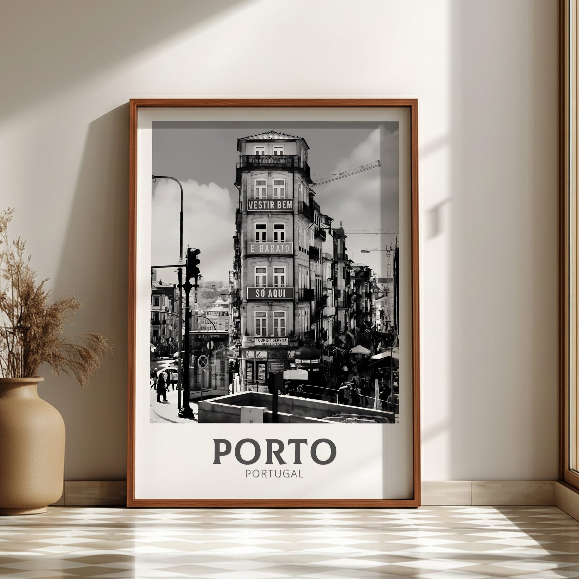 Framed black and white print of Porto, Portugal on a wall with a vase and plant.