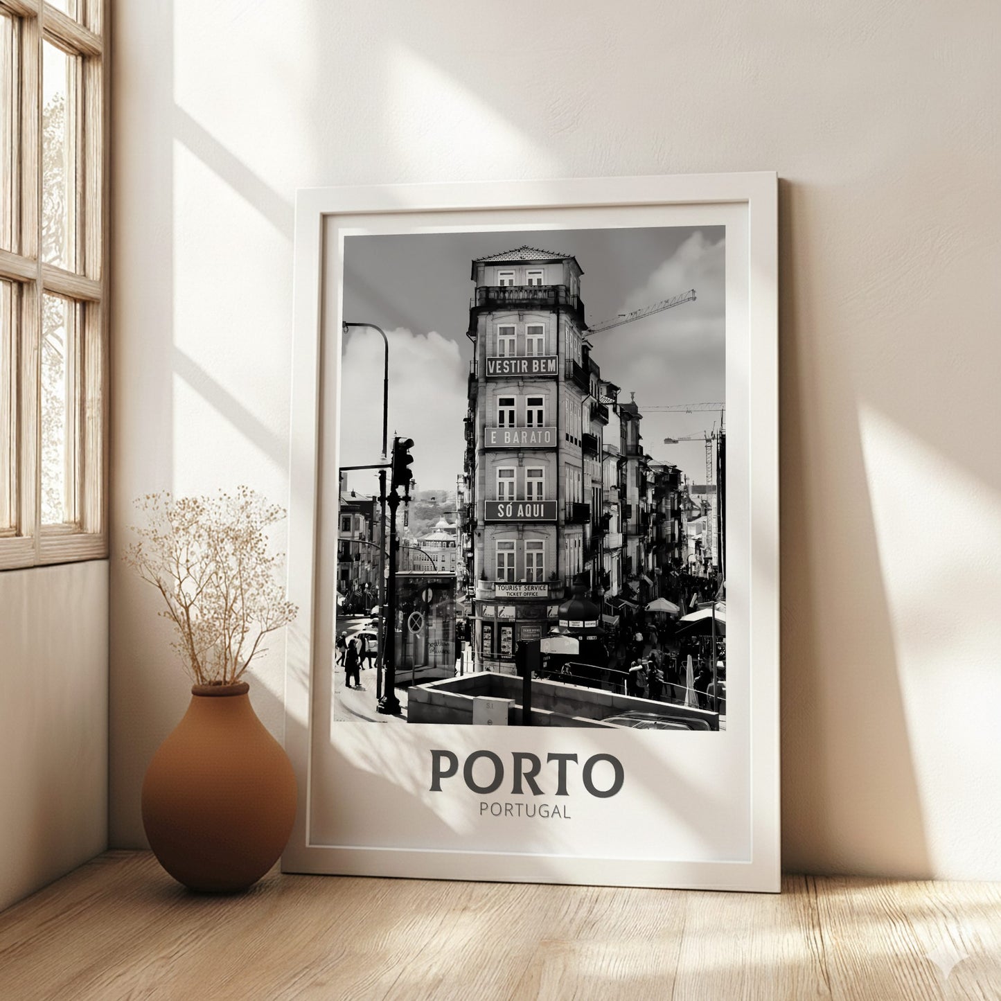 Framed black and white print of a Porto building in a room with a vase and window.