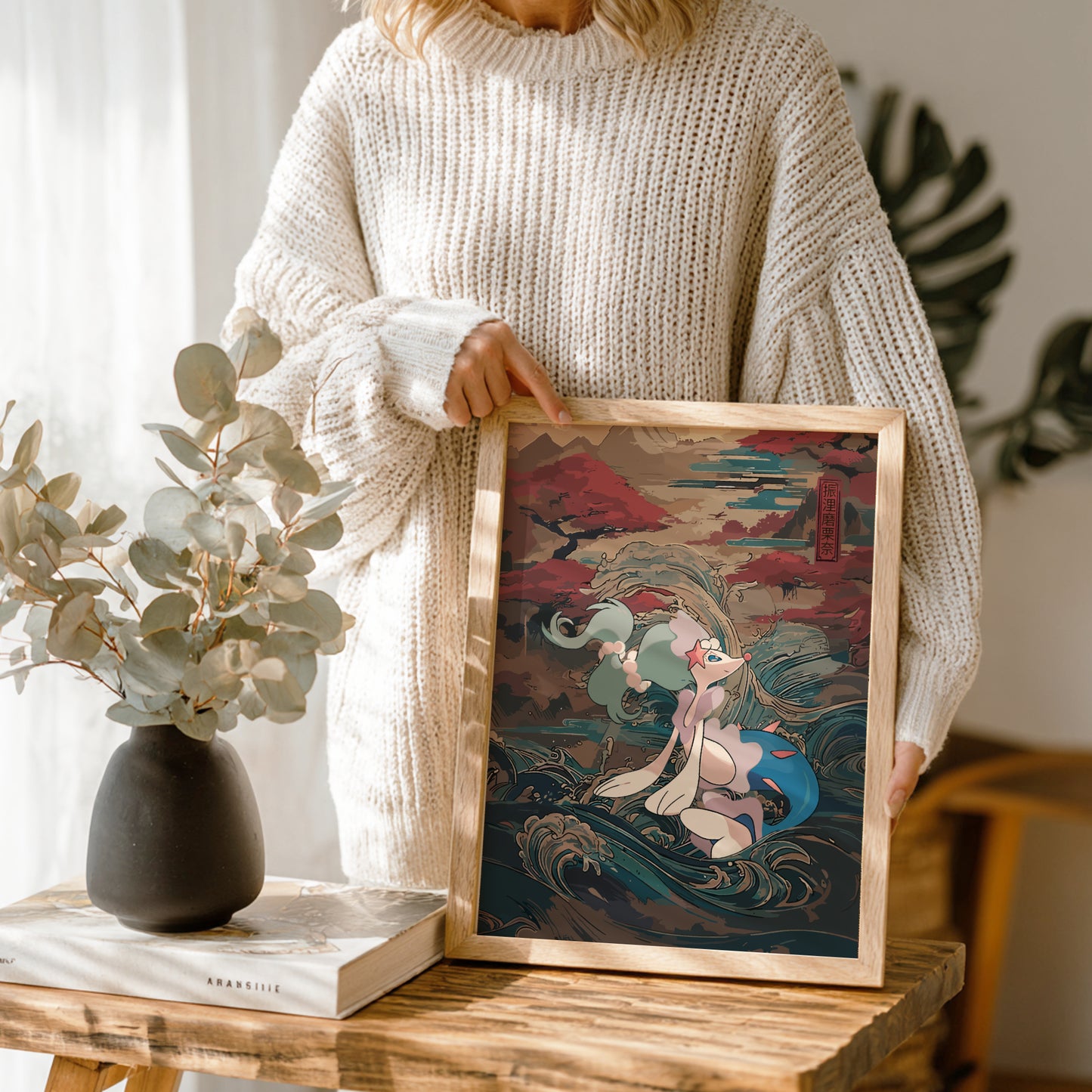Person holding a framed artwork of Primarina Pokemon in a cozy indoor setting