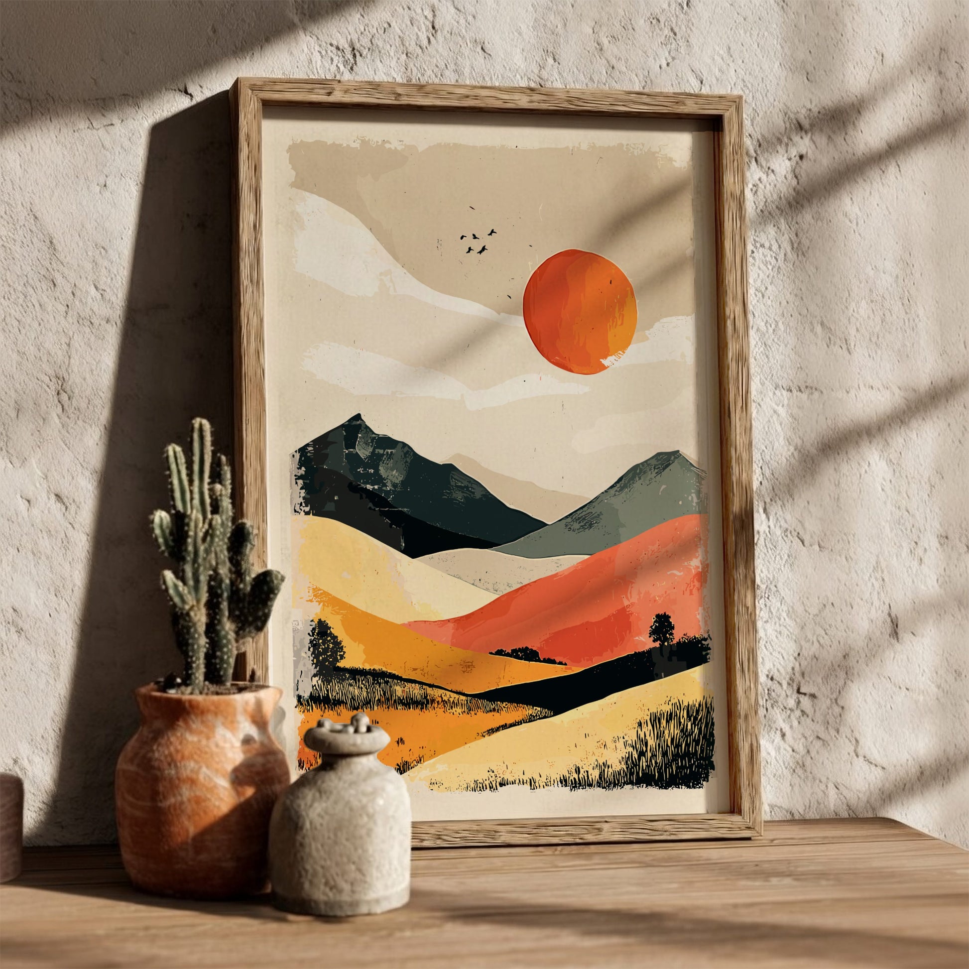 Framed landscape artwork with a sunset over mountains on a textured wall.