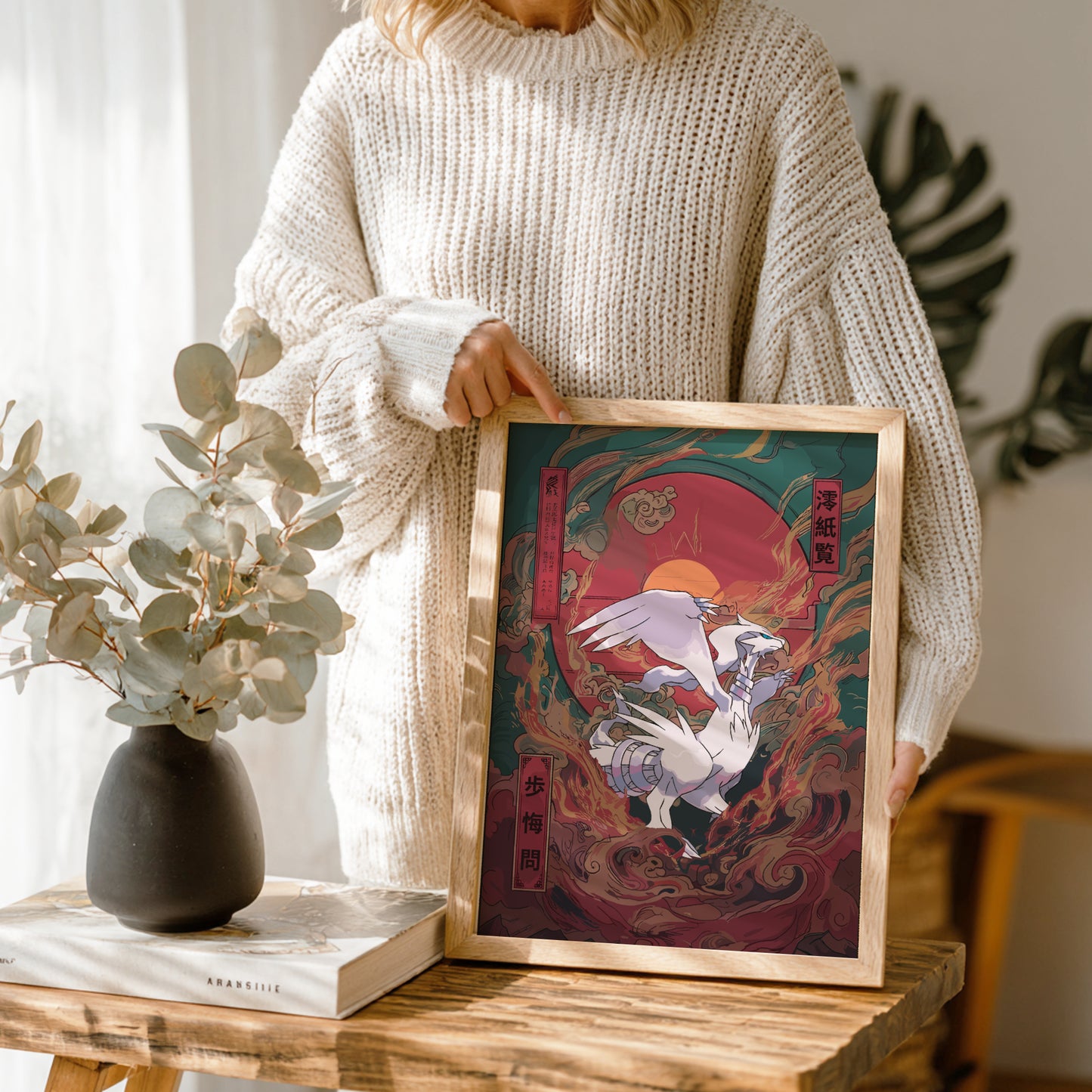 Person holding a framed artwork of Reshiram Pokemon with a nature setting