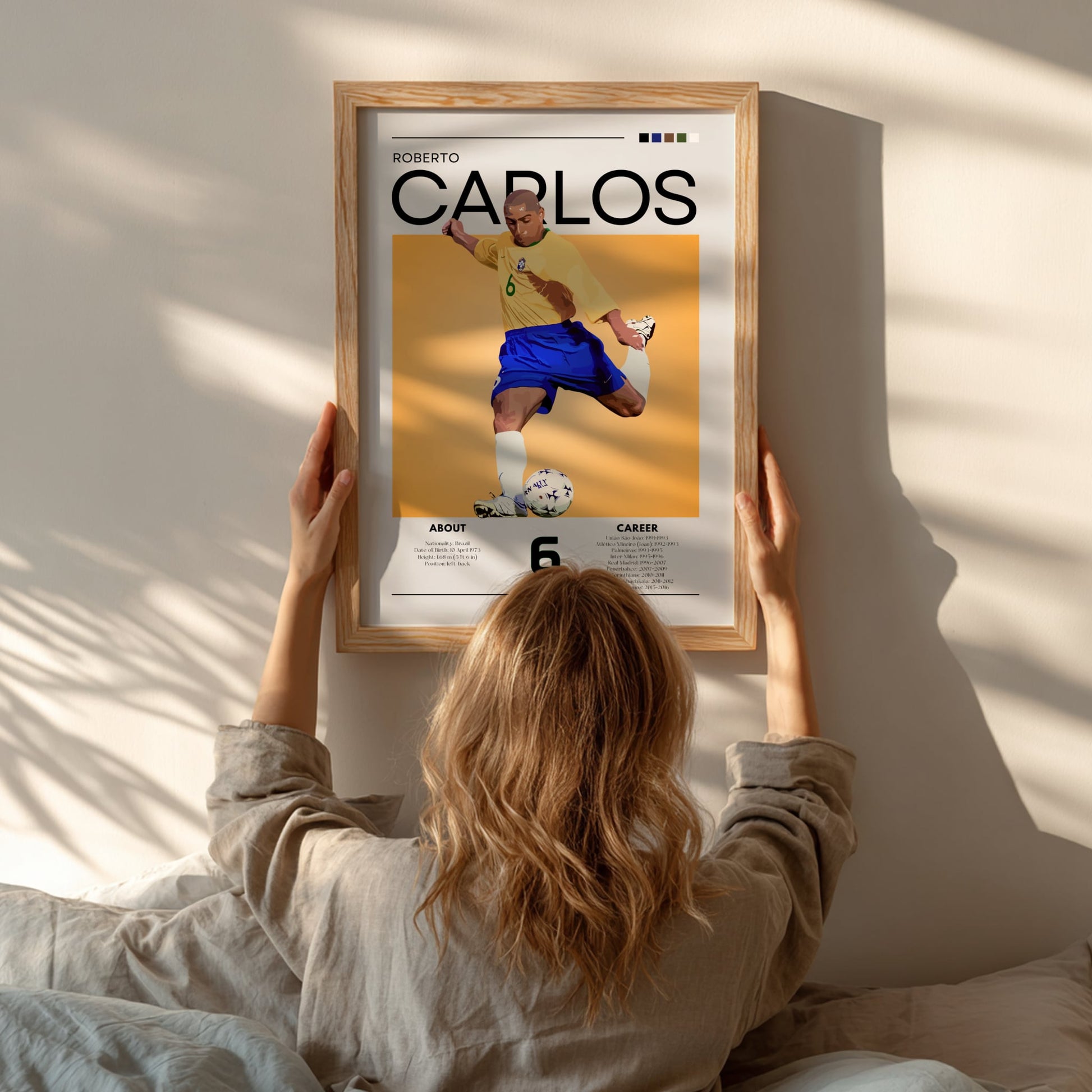 Person hanging a framed poster of Roberto Carlos on a wall