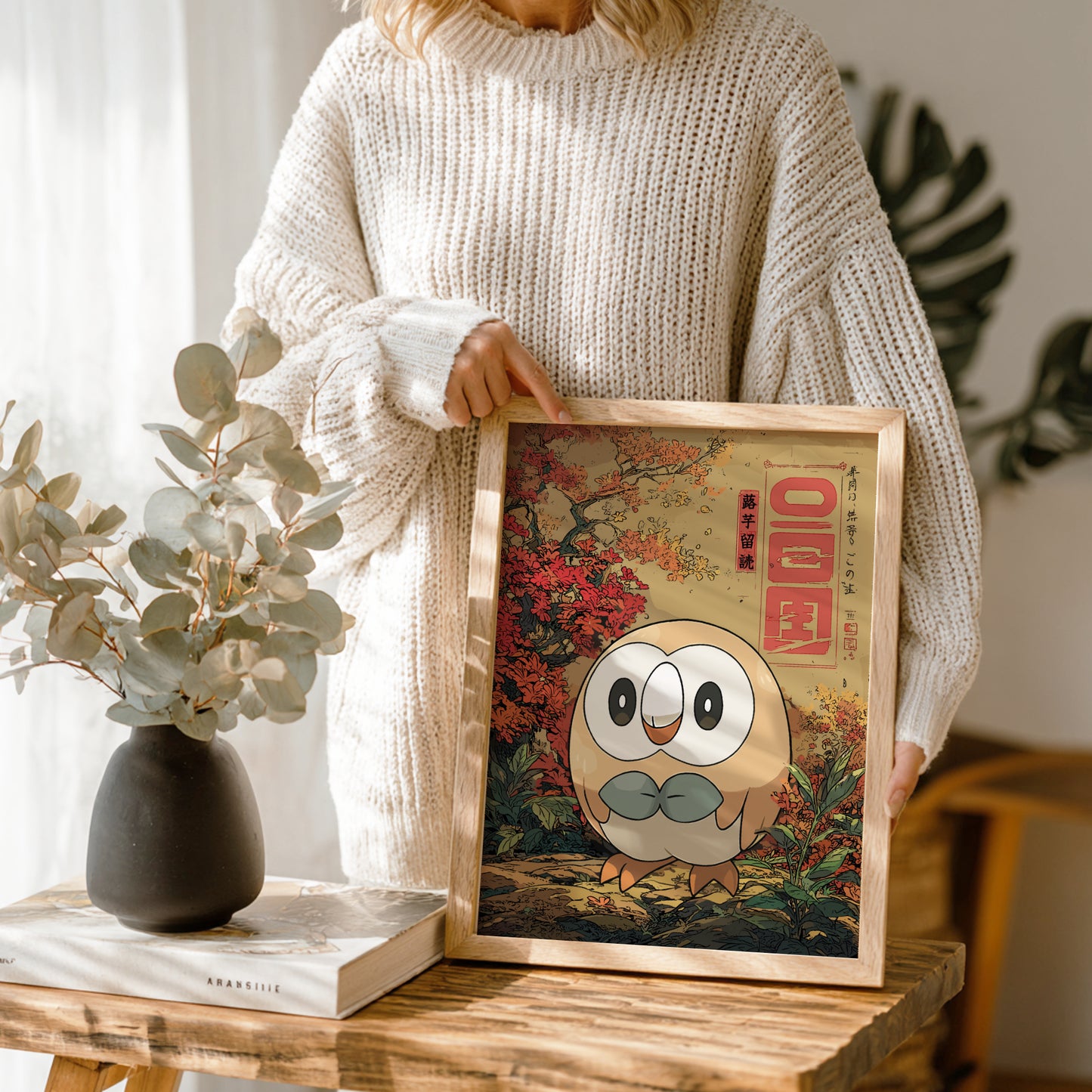 Person holding a framed picture of Rowlet Pokemon with a nature-themed background