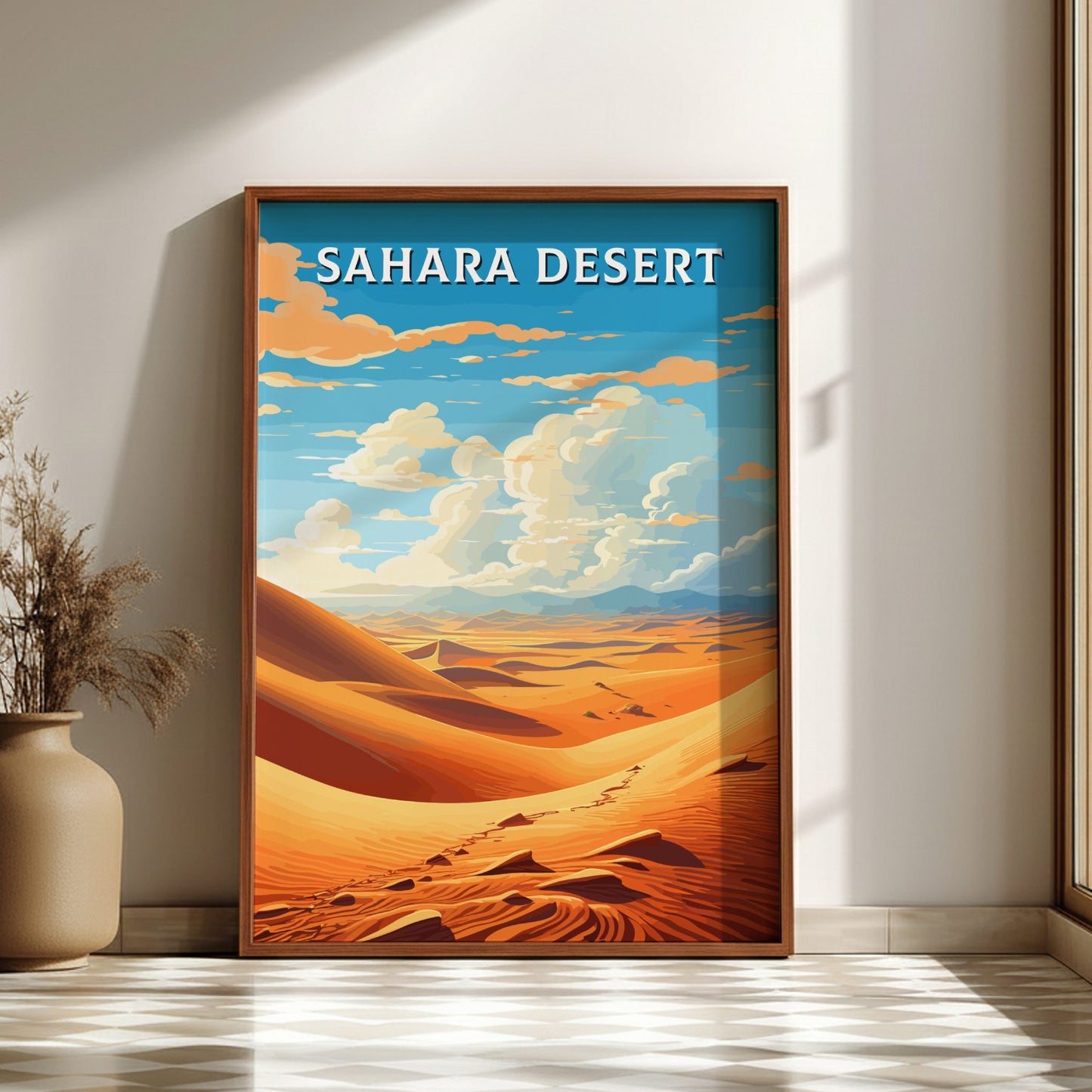 Framed artwork of the Sahara Desert with a blue sky and clouds, displayed on a wall.