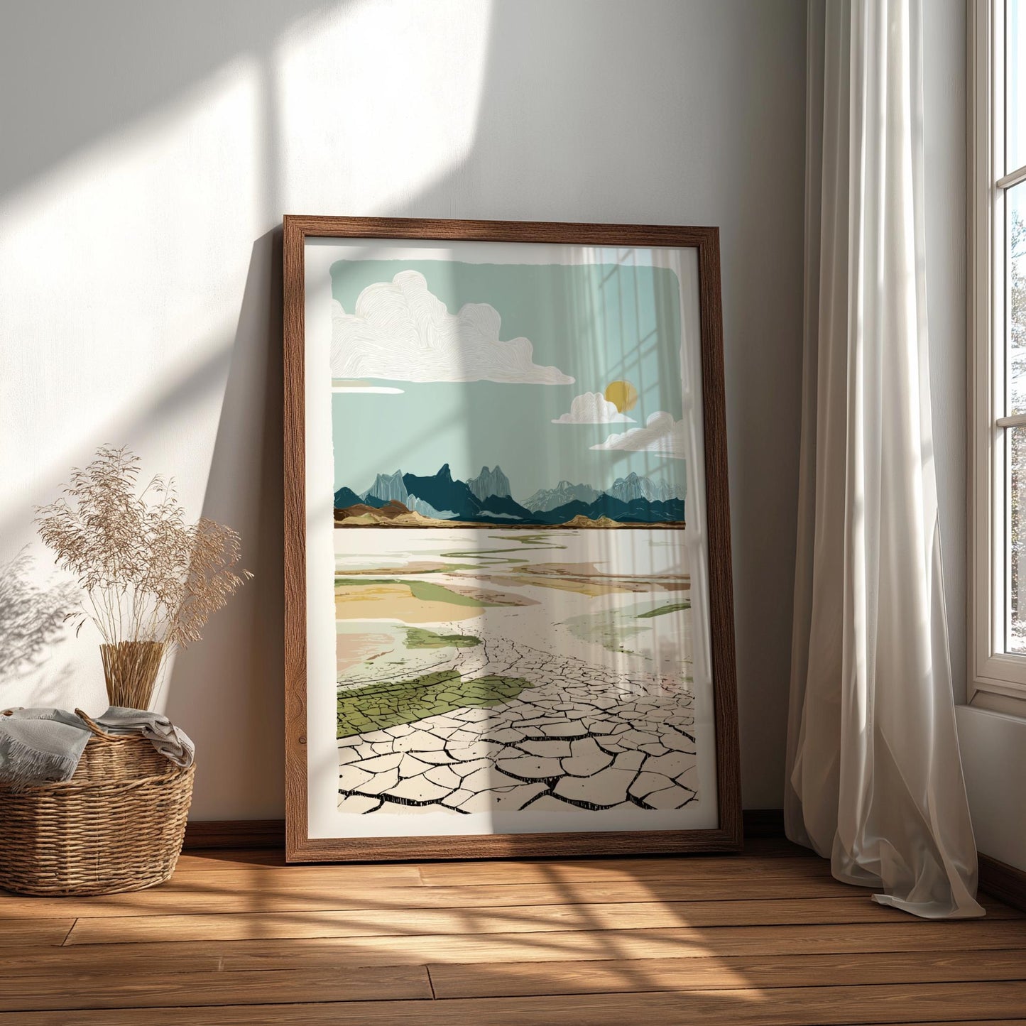 Framed artwork of a landscape with mountains and cracked earth in a room with natural light.