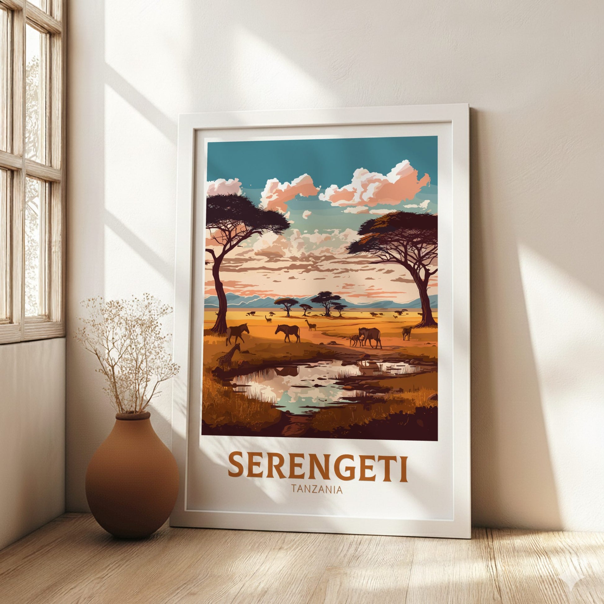 Framed Serengeti Tanzania poster on a wall with a vase and plant in the foreground.