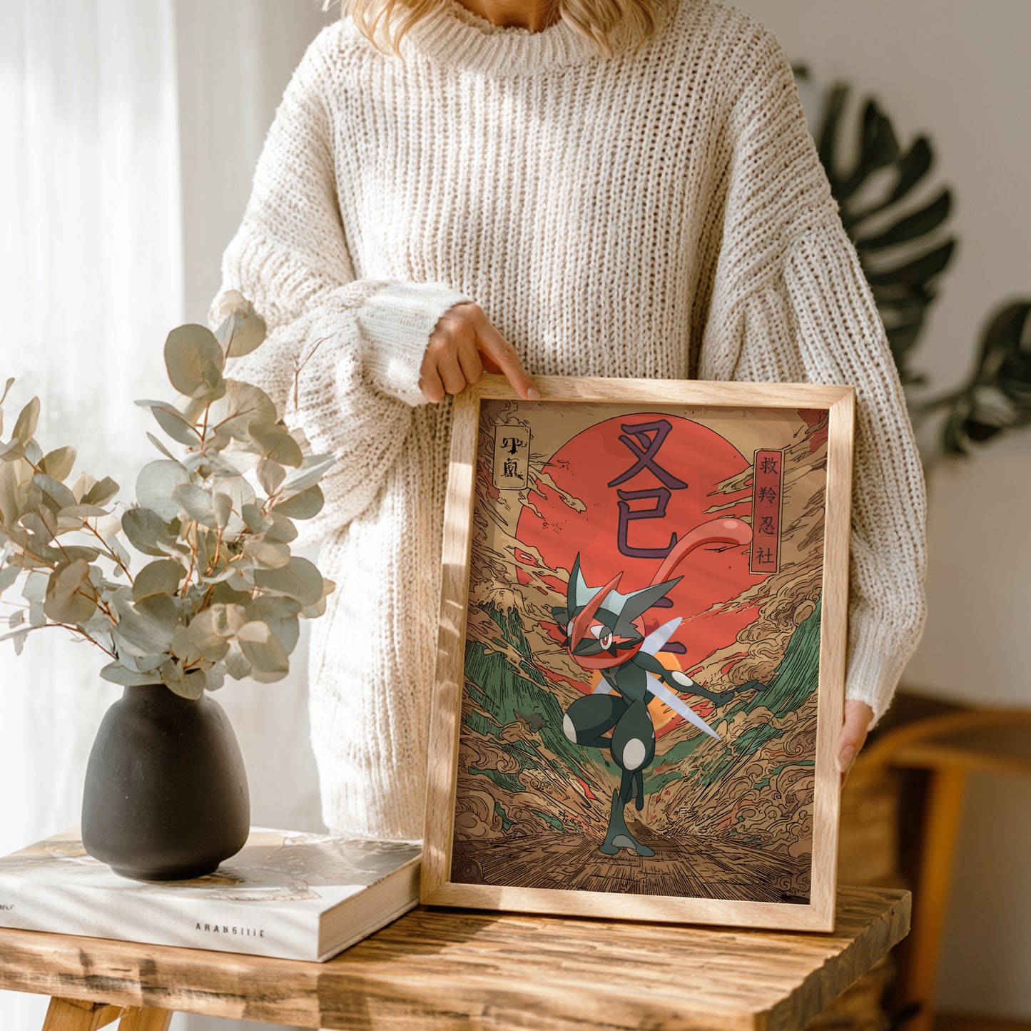 Person holding a framed artwork of Shiny Greninja Pokemon with a red moon in a wooden frame.