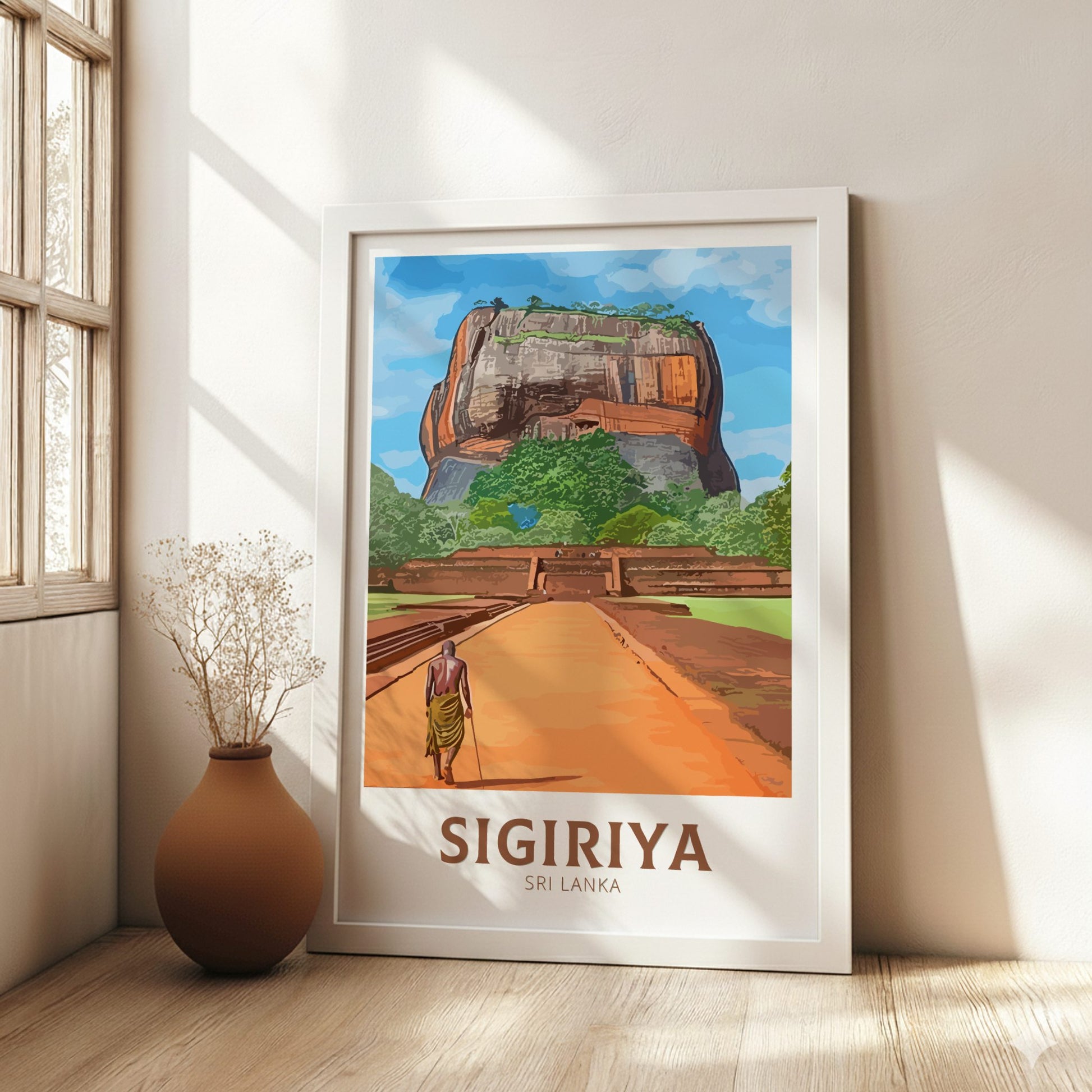 Framed poster of Sigiriya, Sri Lanka with a person walking towards it, in a room with a vase and window.