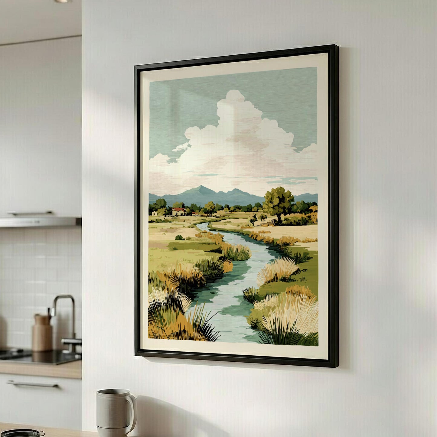 Framed landscape print of a river and mountains on a wall in a kitchen.