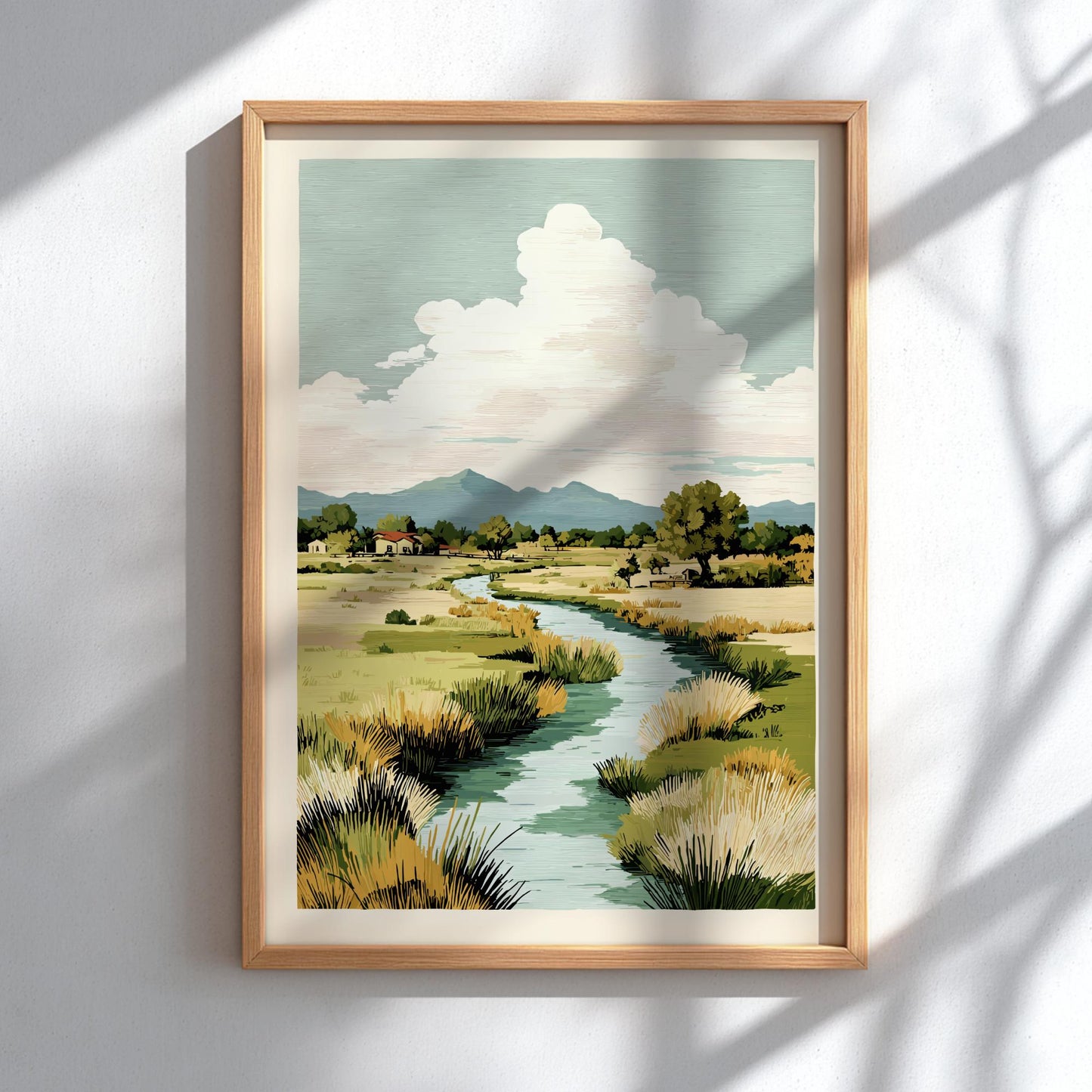 Framed artwork of a landscape with a river, trees, and mountains on a white wall.