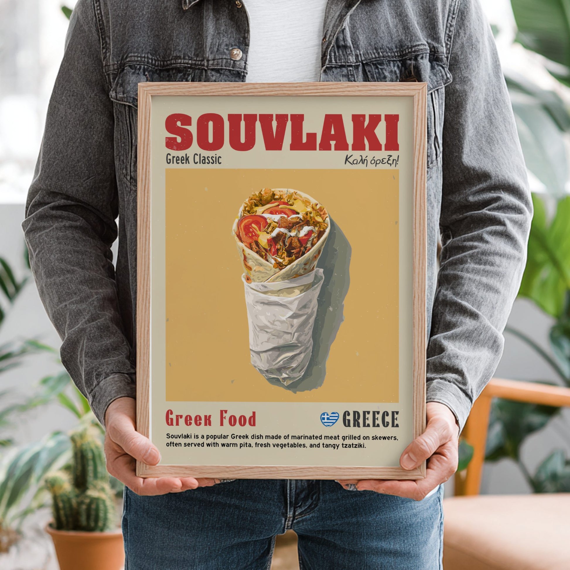 Person holding a framed poster of souvlaki with text and a Greek flag.