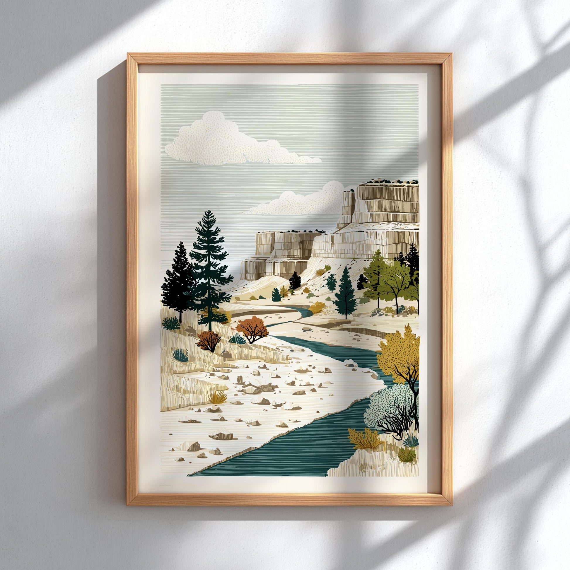 Framed artwork of a mountainous landscape with trees and a stream on a white wall.
