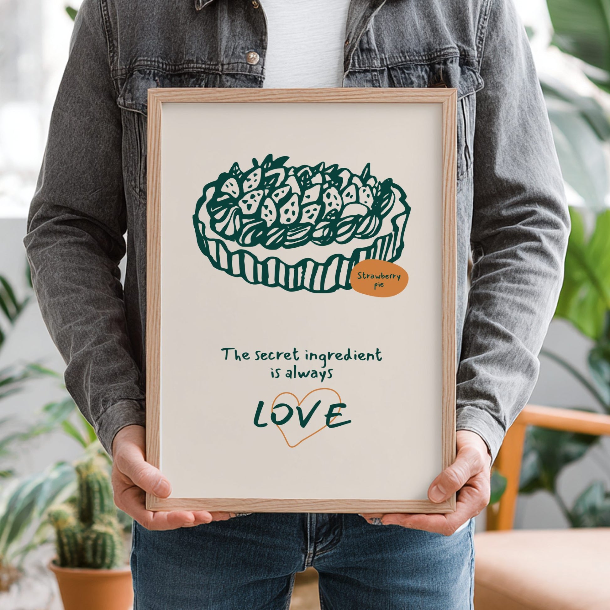 Person holding a framed print with a cake illustration and text.