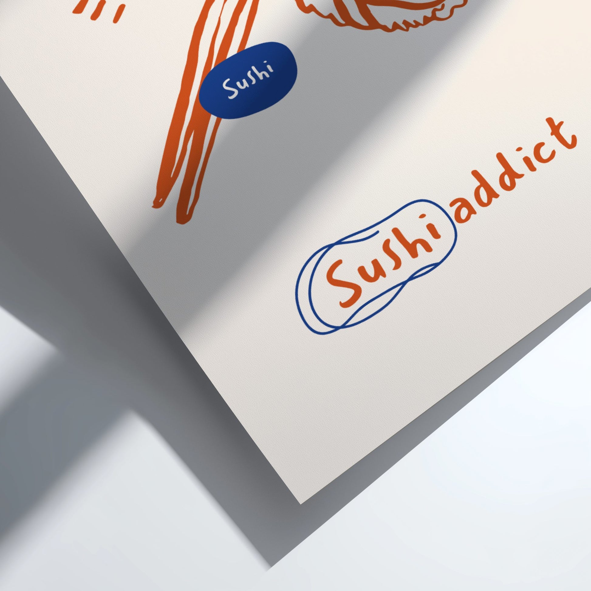 Close-up of a piece of paper with 'Sushi addict' text and illustrations on a light background