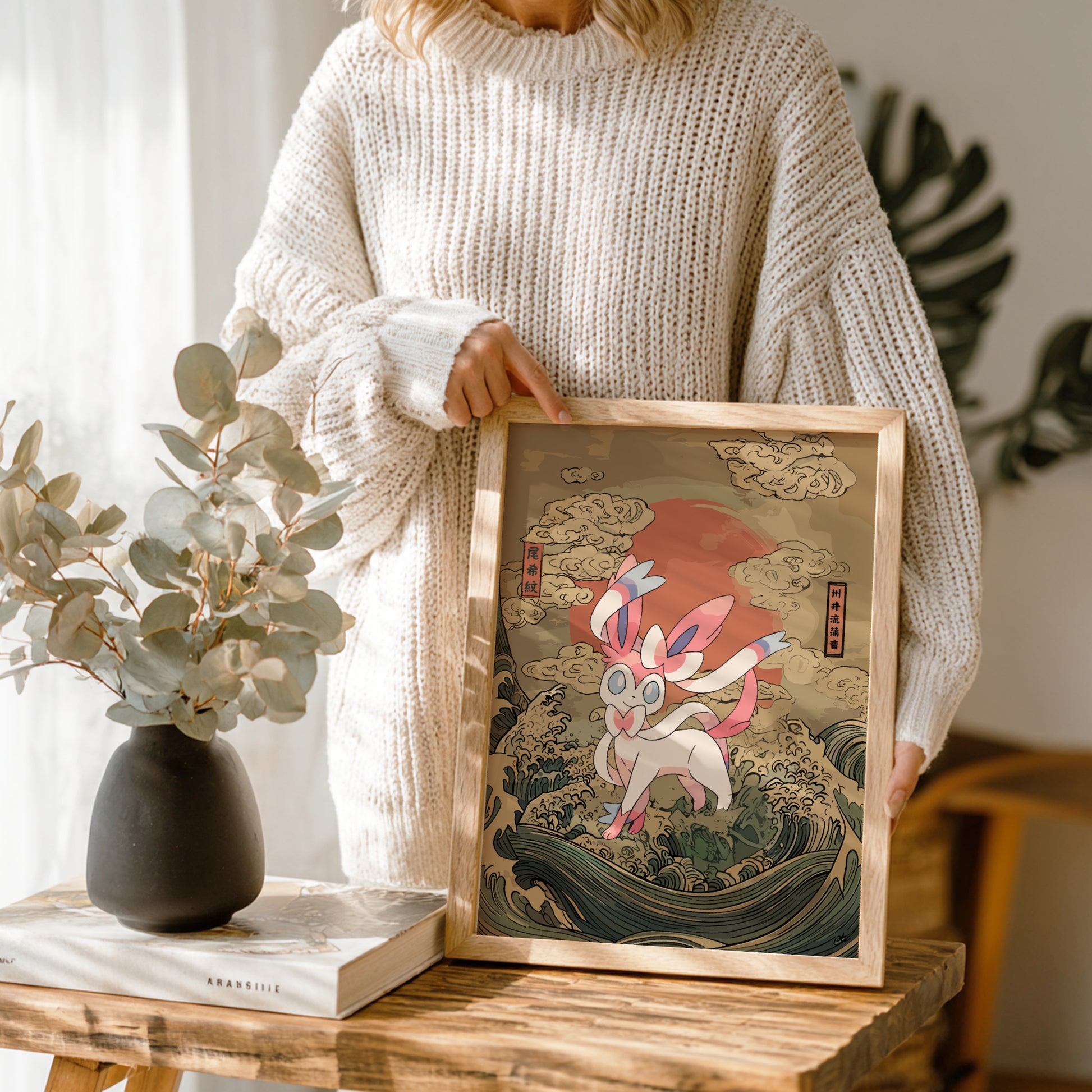 Person holding a framed artwork of Sylveon Pokemon with a natural setting