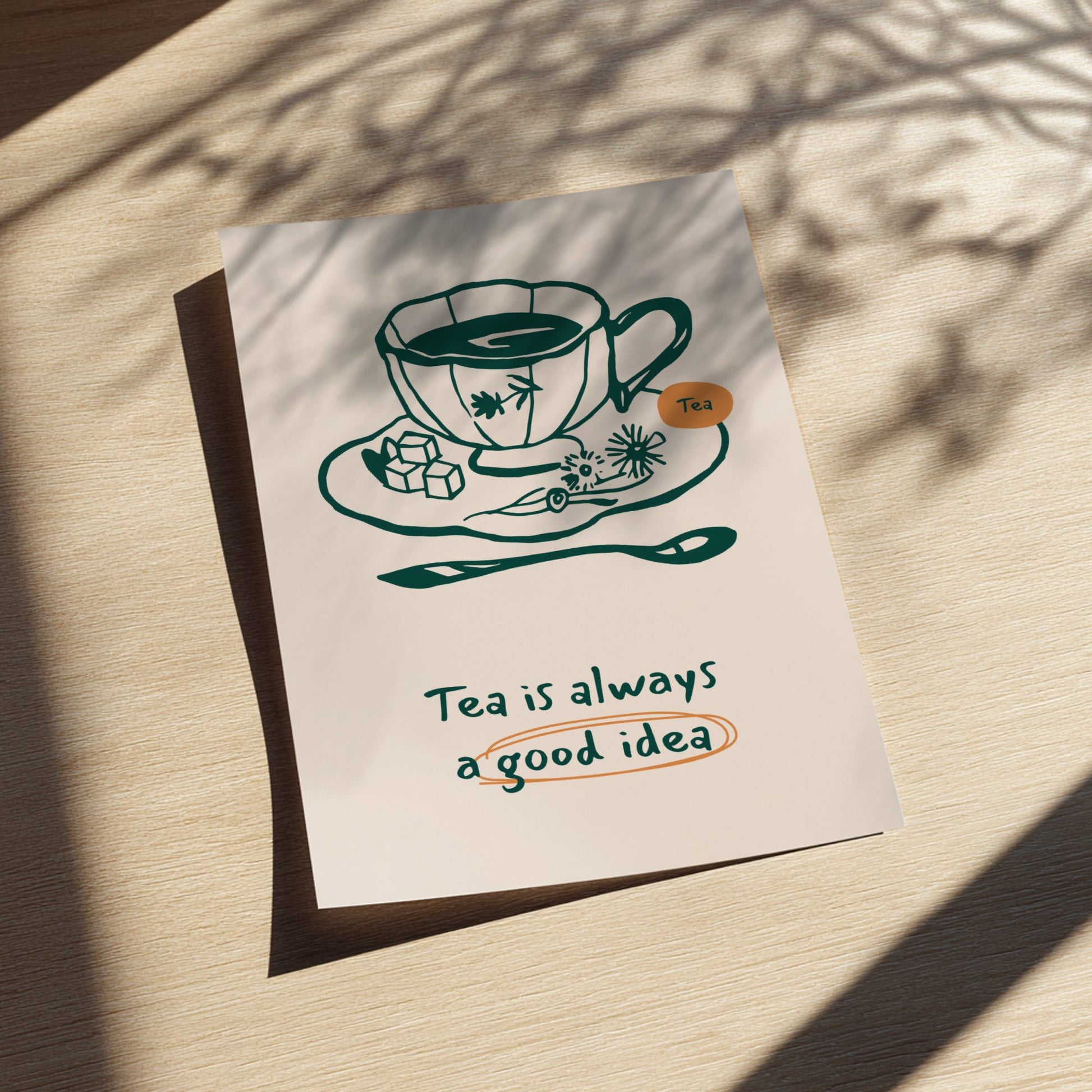 Poster with a tea cup illustration and 'Tea is always a good idea' text on a wooden surface.