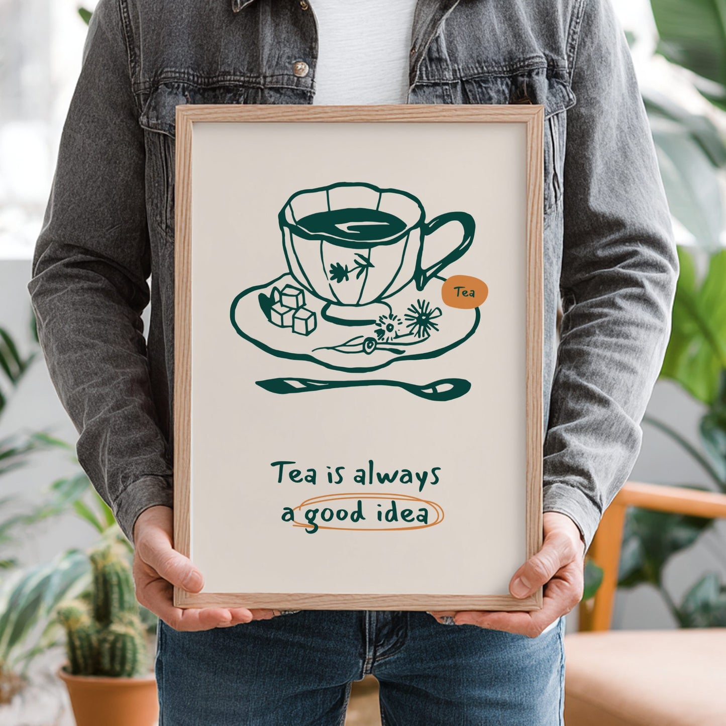 Person holding a framed print with a tea-themed illustration and text.