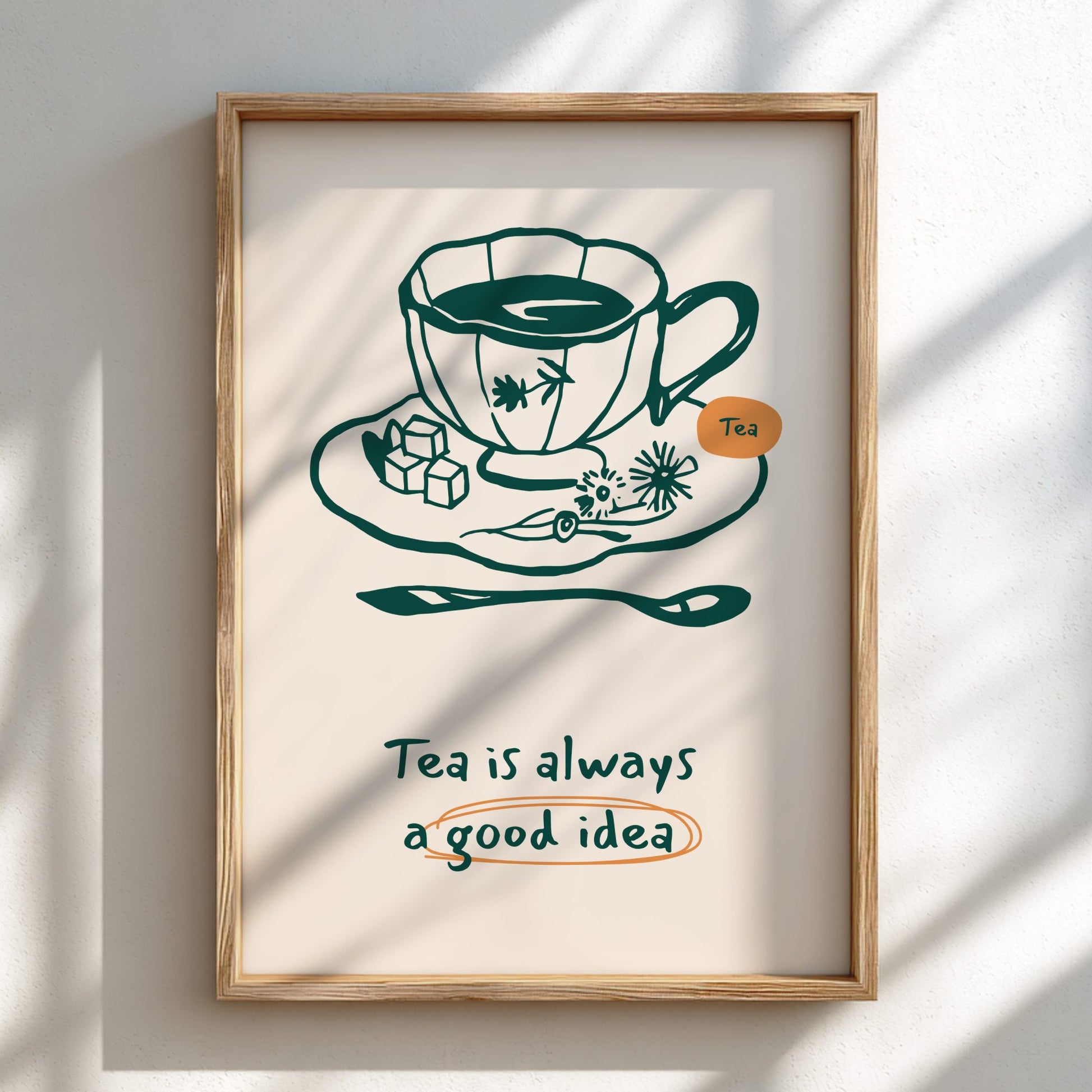 Framed artwork with a teacup illustration and text 'Tea is always a good idea' on a light background.