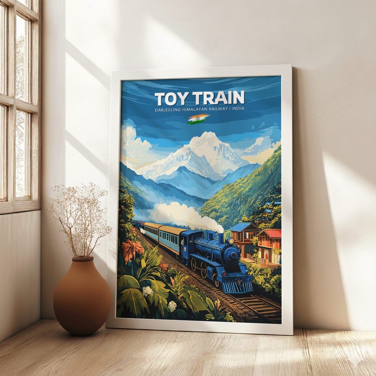 Framed poster of a toy train in a mountainous landscape on a wall in a bright room.