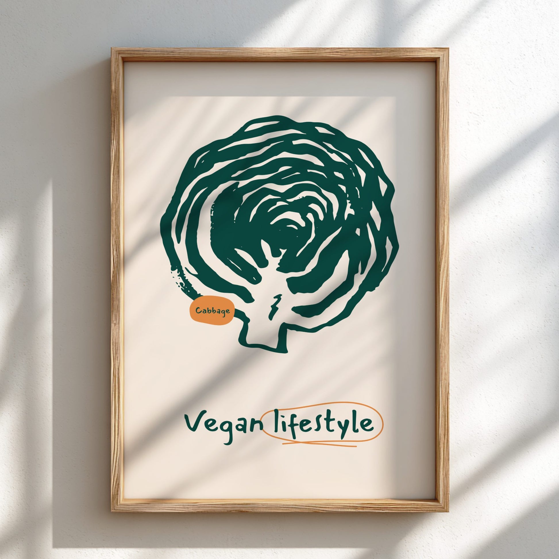 Framed artwork of a green cabbage with 'Vegan Lifestyle' text on a beige background