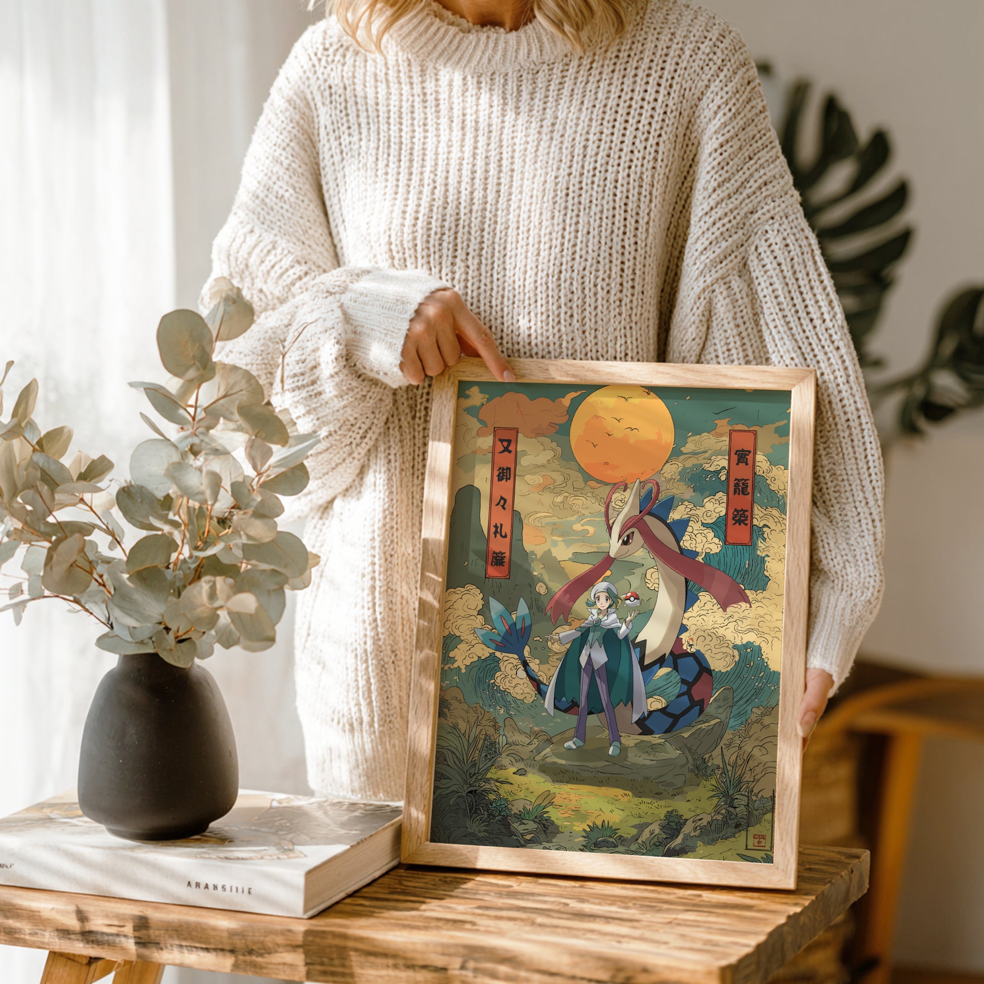 Person holding a framed artwork of Wallace and Milotic Pokemon with a decorative frame on a wooden table.