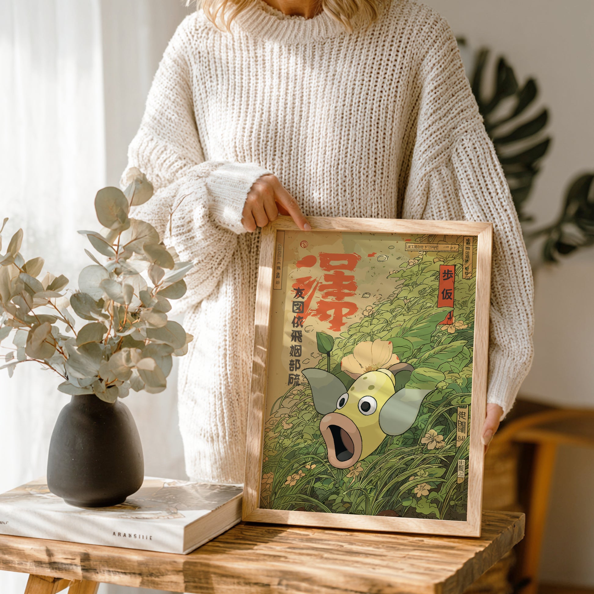 Person holding a framed artwork of Weepinbell Pokemon in a home setting.