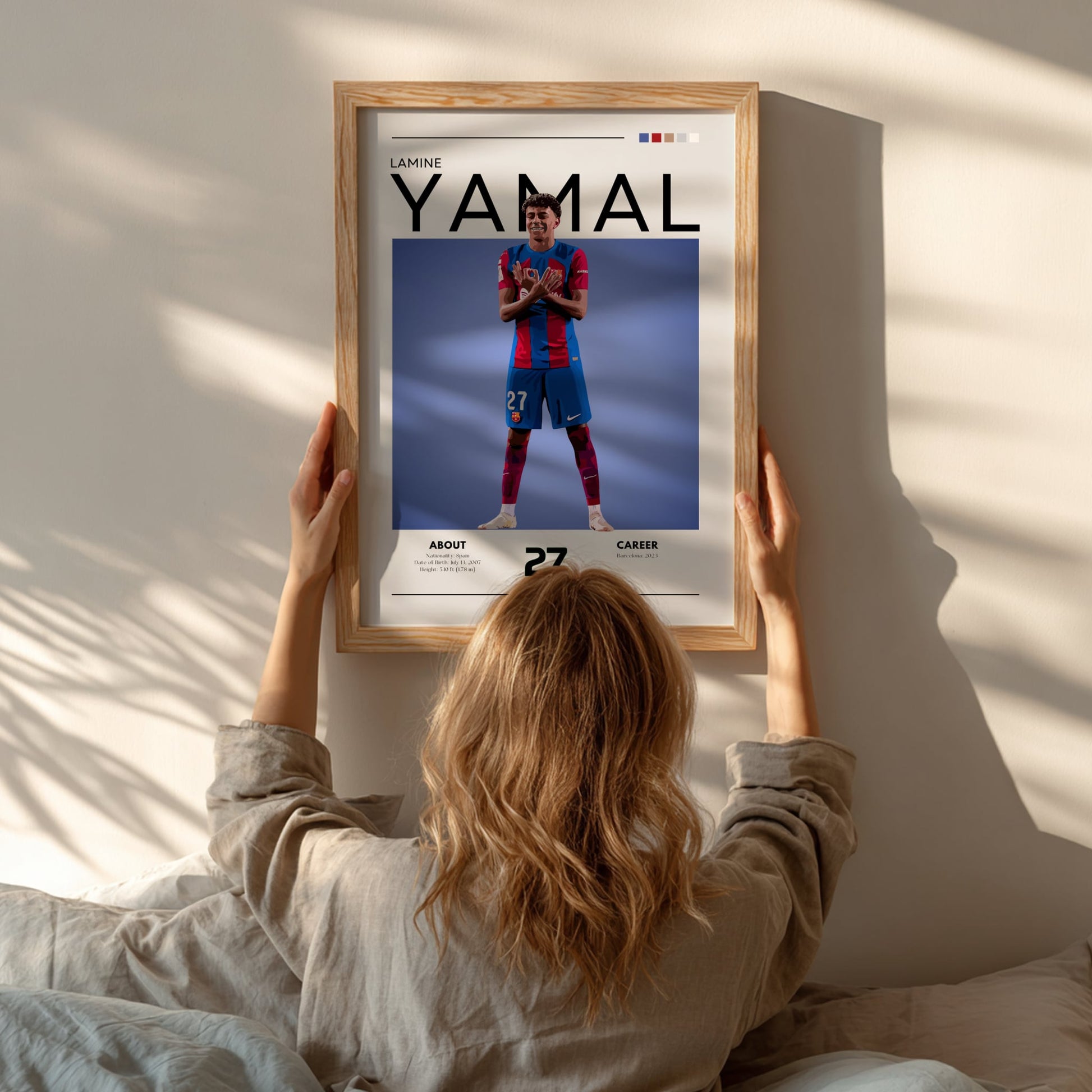Person hanging a framed poster of a soccer player named Yamal on a wall.