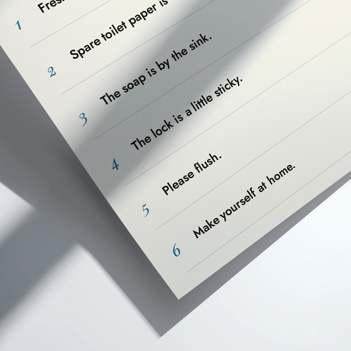 A close-up of a printed checklist sheet with numbered instructions in blue text on an off-white background, photographed at an angle with soft shadows.