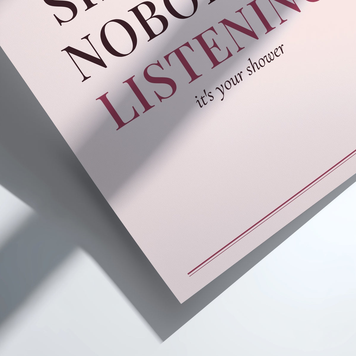 A close-up of a printed sign or card with partial text reading 'LISTENING' and 'it's your shower' in dark red and black lettering on a pale pink background, photographed on a white surface with a strong diagonal shadow.