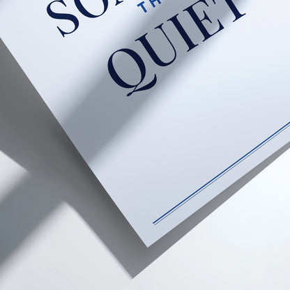 A close-up of a white printed card or poster with large navy serif text reading 'SO THE QUIET' and a thin navy line near the bottom, photographed on a white surface with strong diagonal shadows.