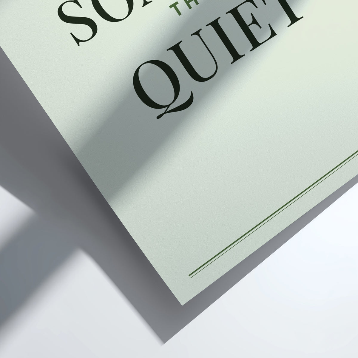 A close-up of a printed card or poster with the words 'SO Quiet' in large black serif lettering on a pale mint-green background, photographed on a white surface with a soft shadow.