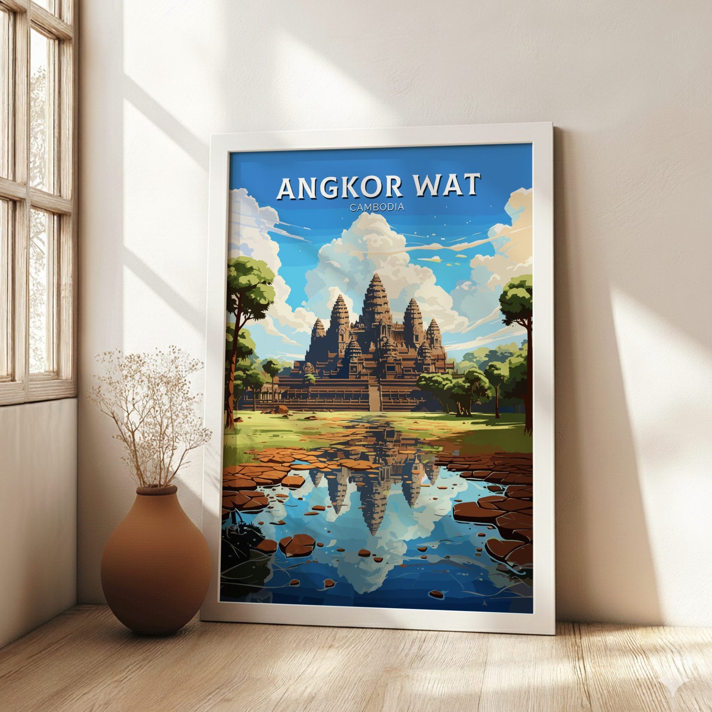 Framed poster of Angkor Wat in a room with a vase on a wooden floor.