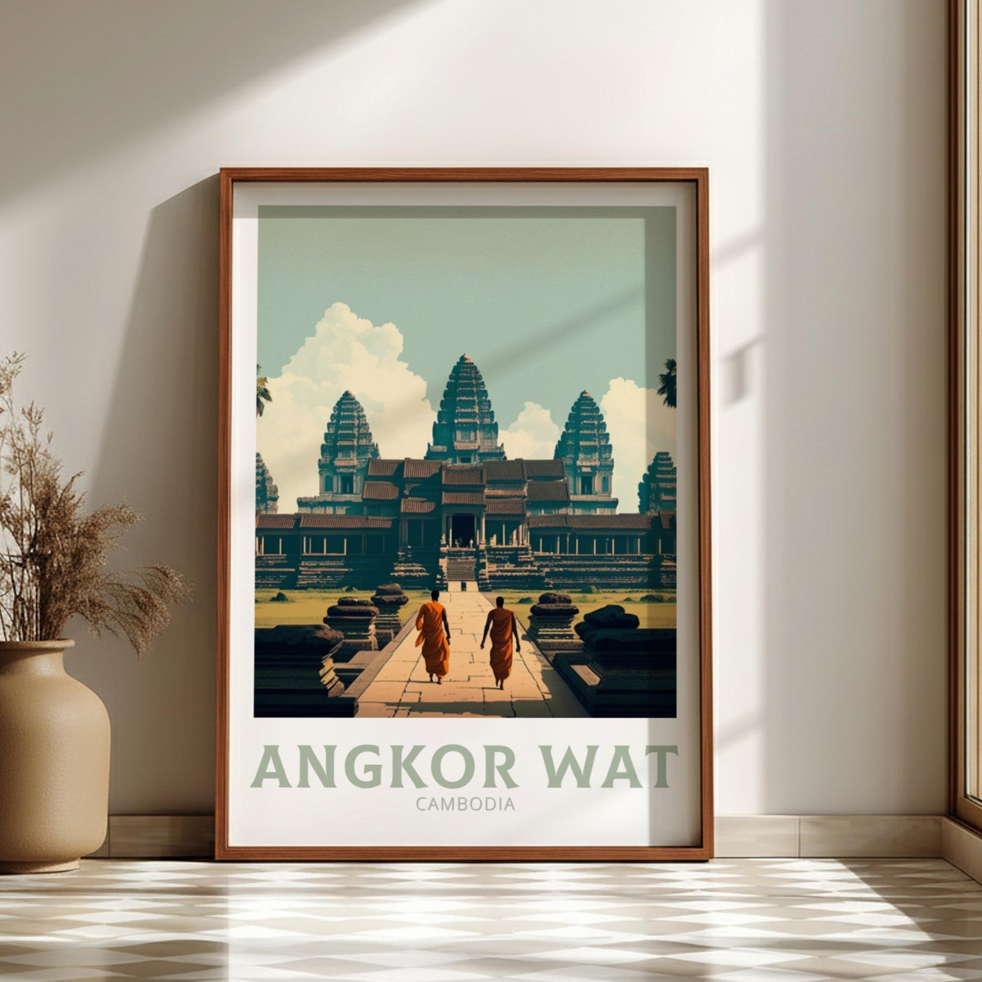 Framed poster of Angkor Wat with two people walking towards it, on a wall.