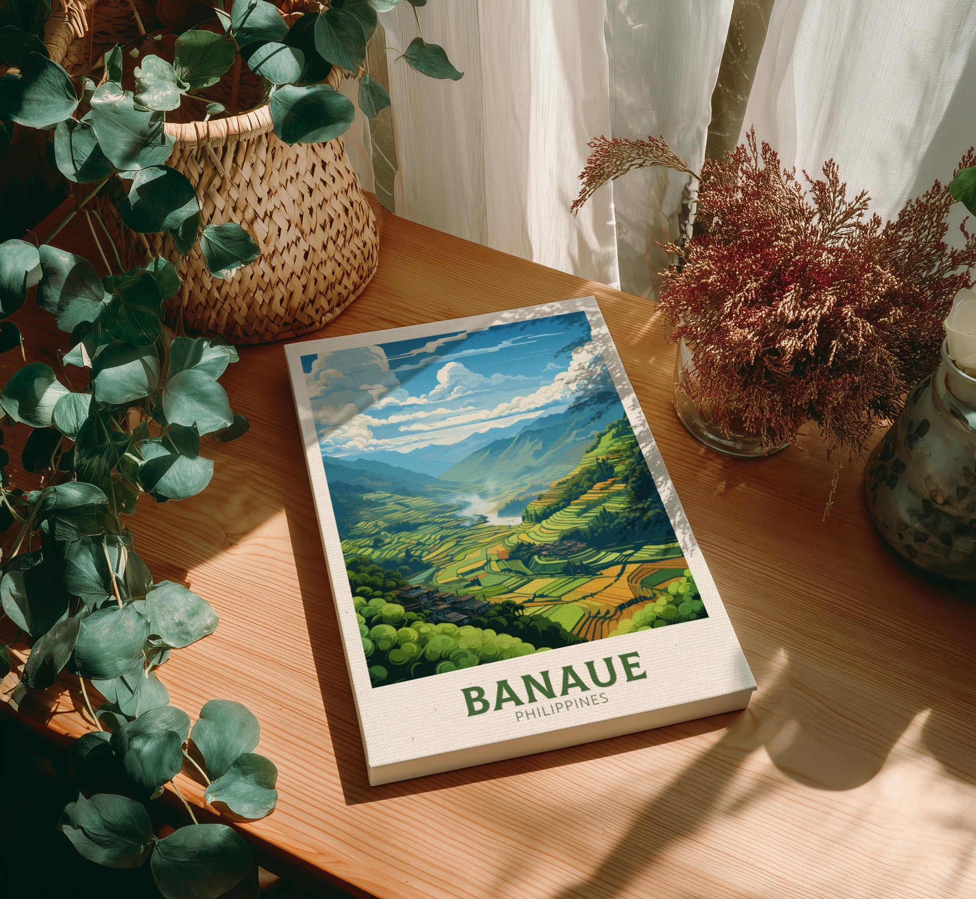Canvas with a scenic cover of Banaue, Philippines on a wooden table with plants.